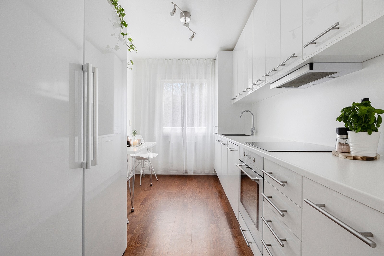 Kjøkkeninnredning med slette høyglansfolierte fronter, ventilator og integrert stekeovn, koketopp og oppvaskmaskin. Galleribilde
