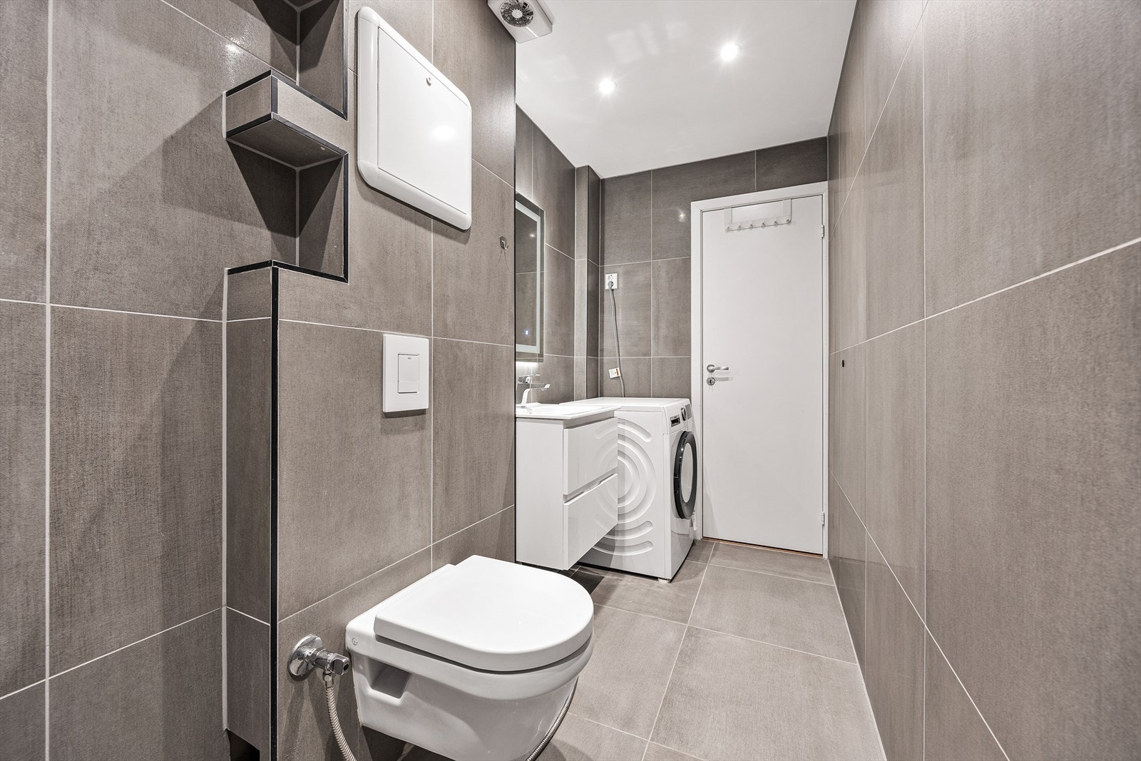 Badet er romslig med moderne, store fliser på gulv og vegger. Galleribilde