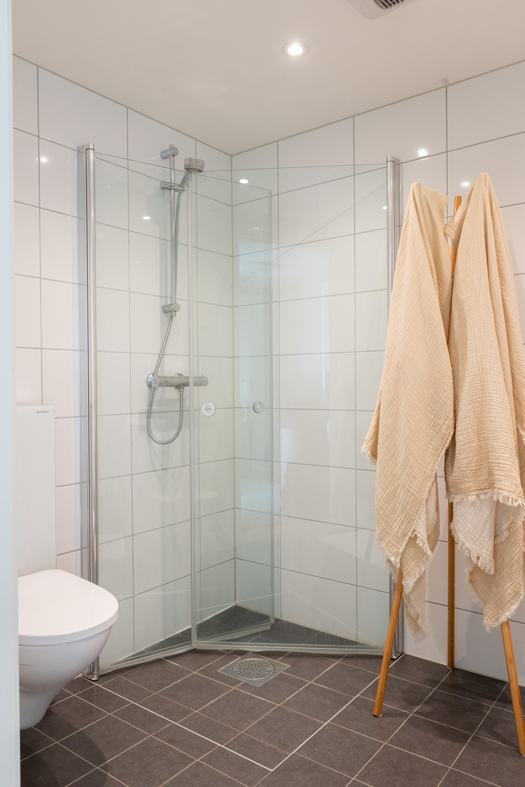Badet er innredet med vegghengt klosett, servant med innredning, speilskap med lys og dusjhjørne med svingbare glassdører. Galleribilde