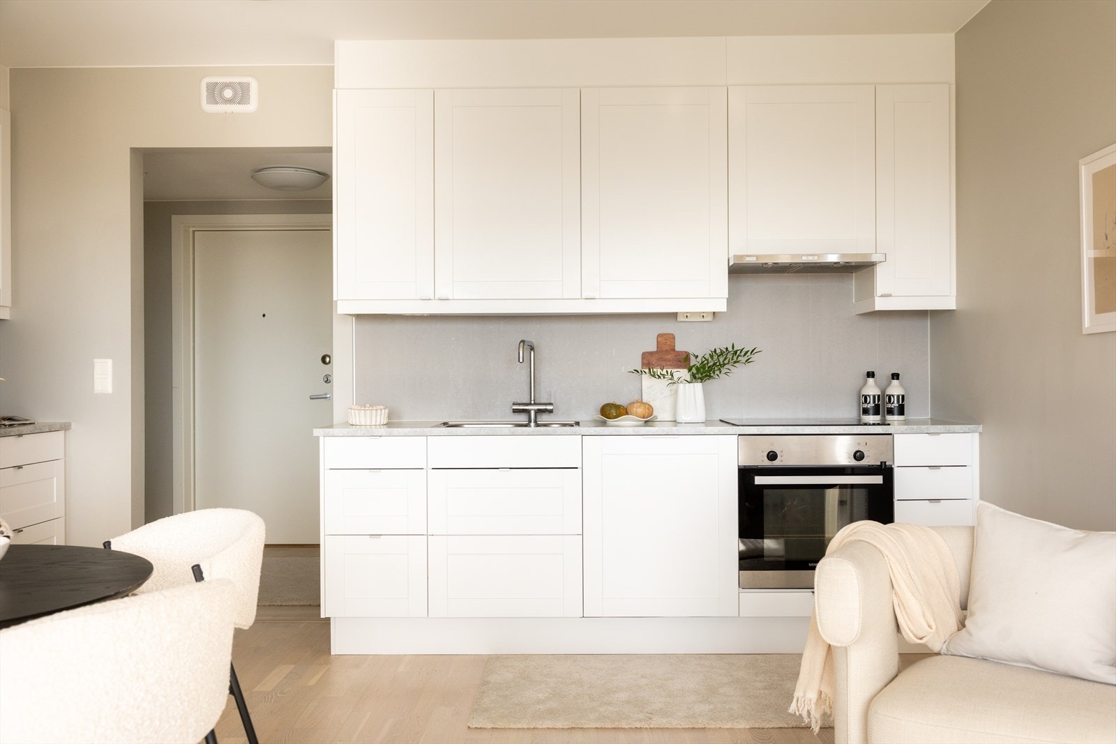 Stilrent kjøkken fra Marbodal hvor kjøkkeninnredningen består av hvite, glatte fronter og benkeplate av laminat med nedfelt vask- og skyllekum. Galleribilde