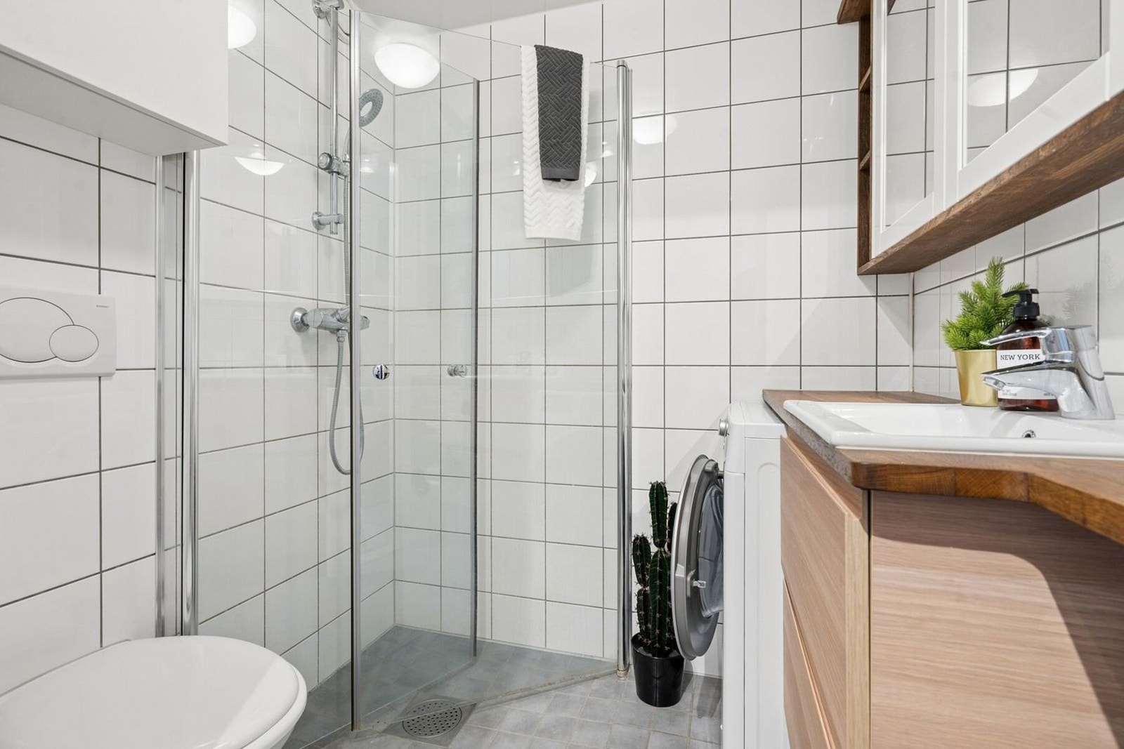 Badet er lyst og trivelig, og har eksklusivt, plassbygget møblement i eik samt kombinert vaskemaskin/tørketrommel (7/4 kg vask/tørk) med WiFi-funksjon som medfølger handelen. Galleribilde