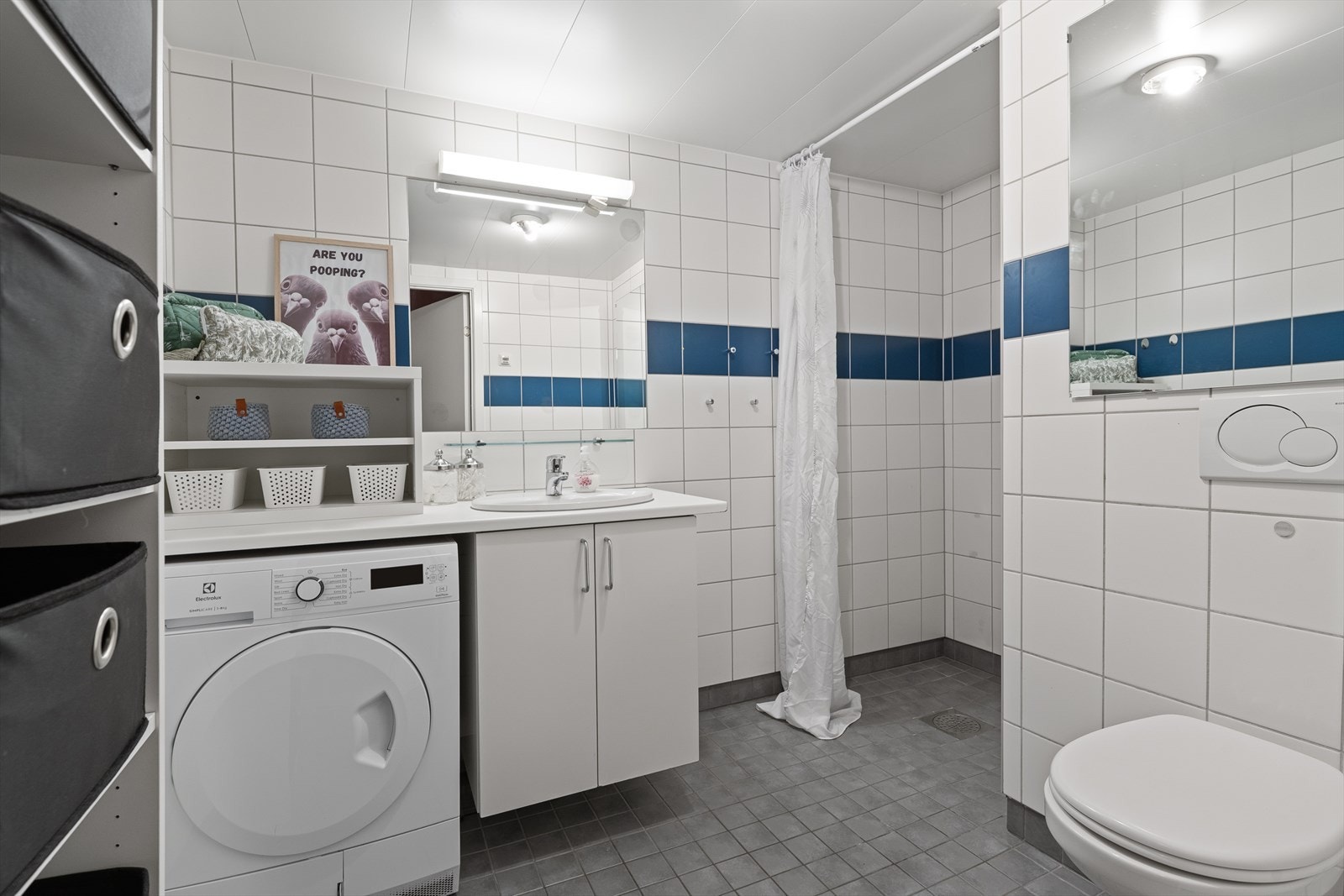 Badet er innredet med servant i innredning, overhengende speil med lys, vegghengt toalett samt hyller og skap. Galleribilde