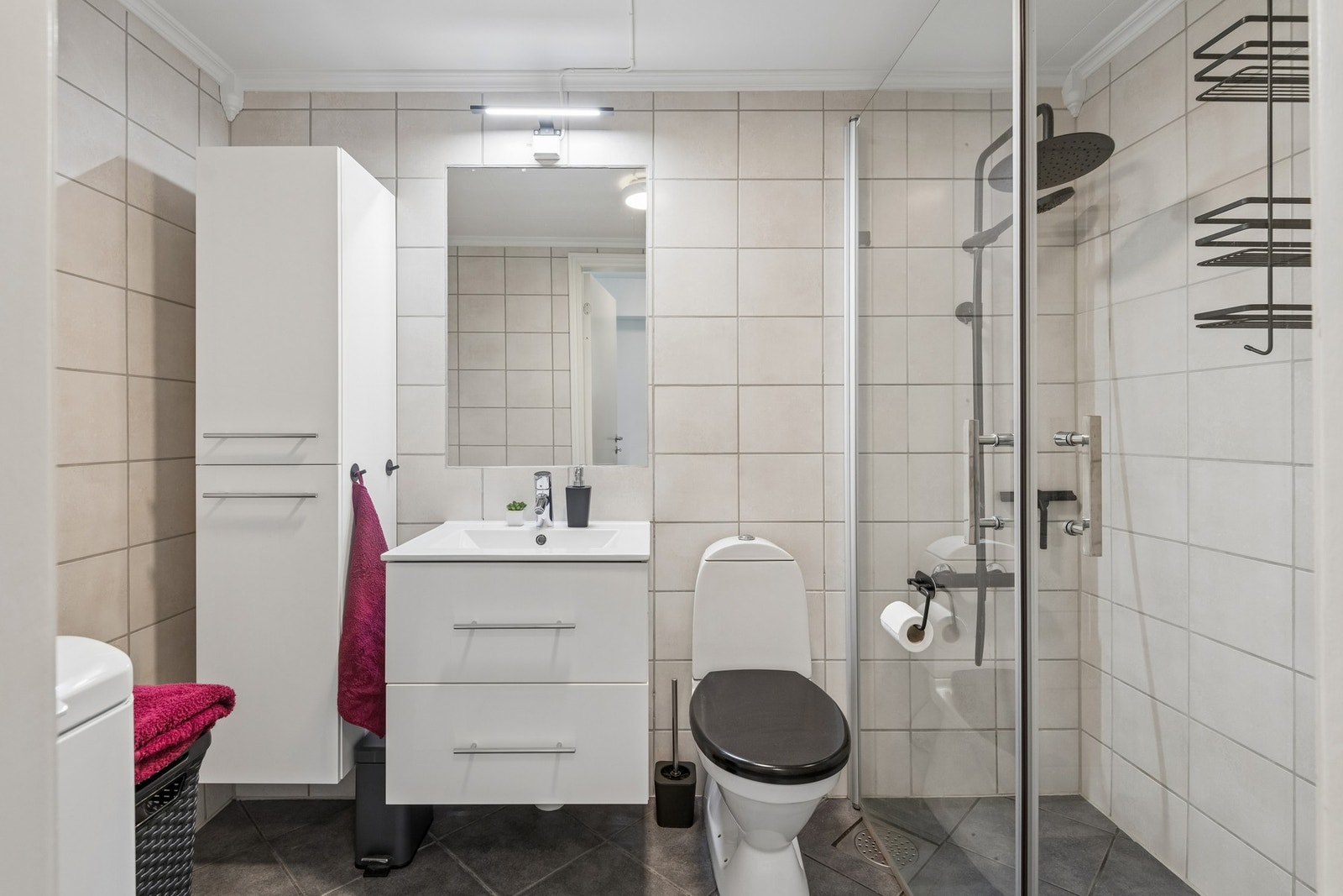Flislagt bad med dusjssone, toalett og servantskap. Gulvet har varmekabler i gulv. Galleribilde