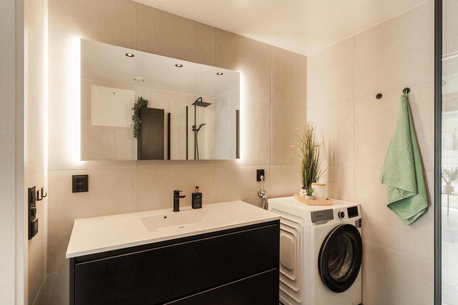 Badet holder en moderne standard med flislagte overflater, gulvvarme og opplegg for vaskemaskin. Galleribilde