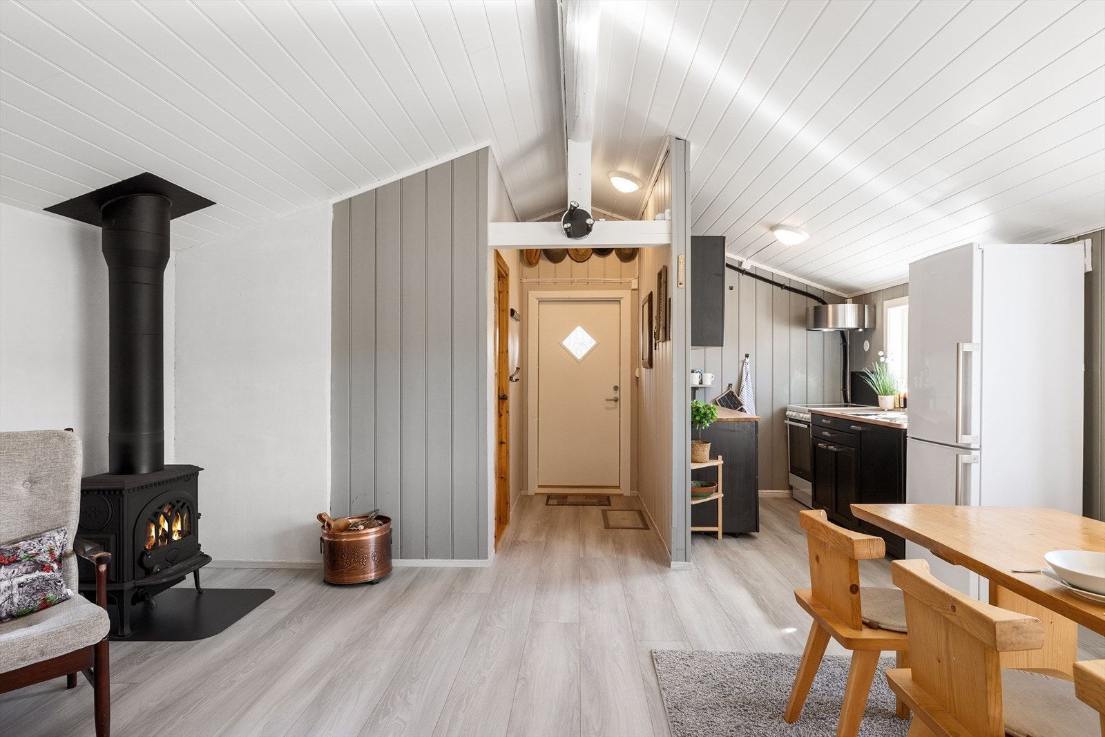 Innbydende stue med hvitmalt skråtak og elegant glasspeis som skaper lun atmosfære. Galleribilde