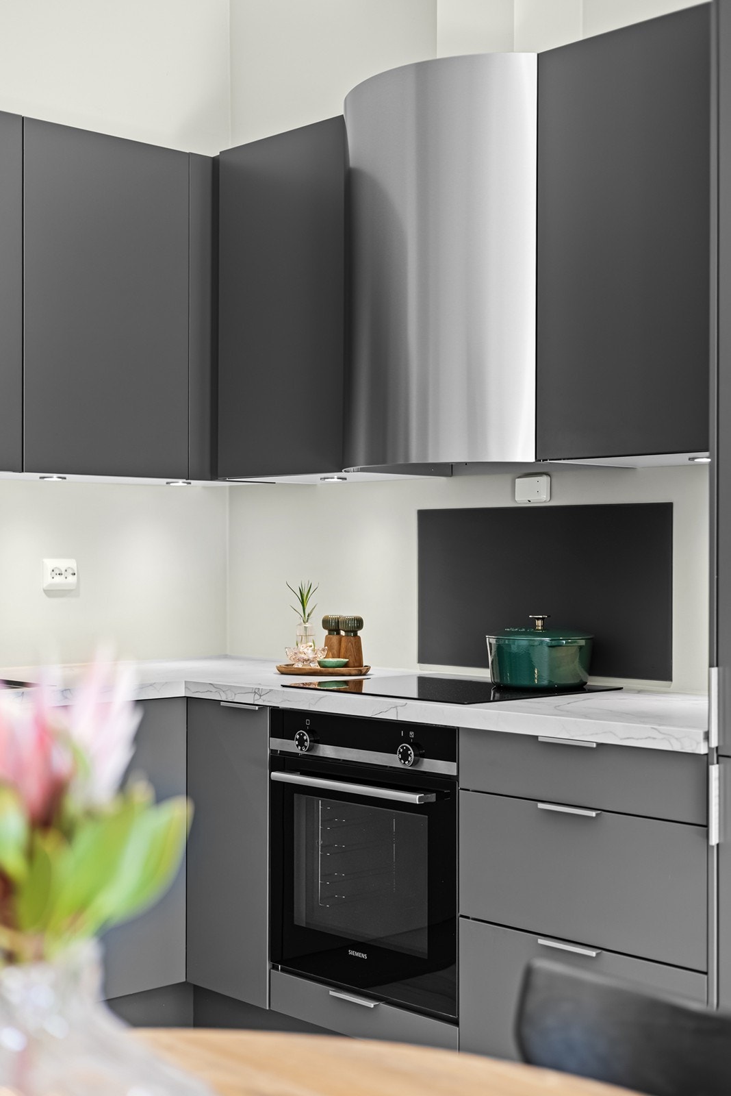 Det er belysning under overskapene samt glassplate på vegg over platetopp og ved vaskekum, noe som gir både et stilrent uttrykk og enkel rengjøring. Galleribilde