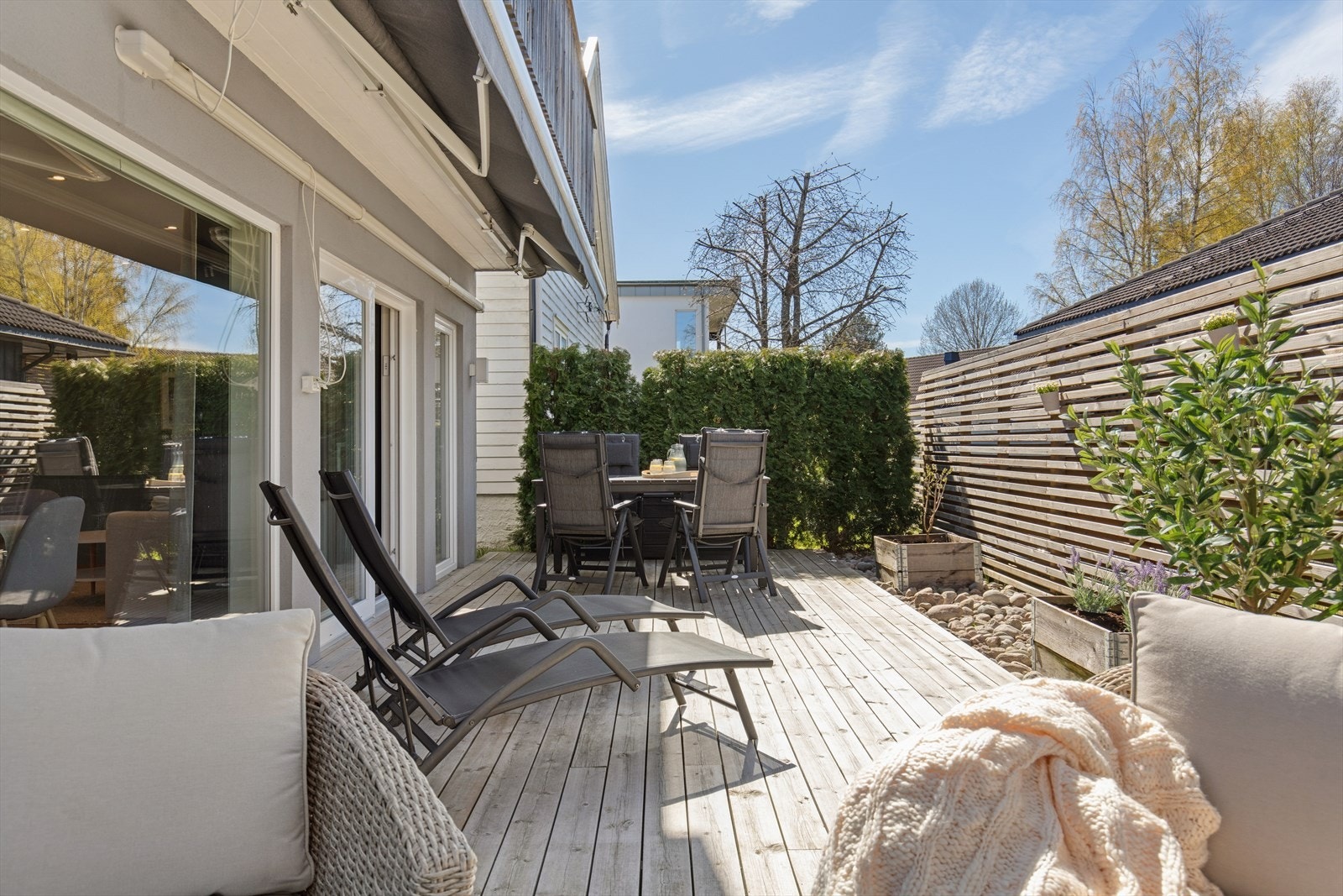 Boligens platting er en forlengelse av stuen på sommertider og har en stor, elektrisk markise som gjør at du kan nyte uteområdet uansett vær. Det er lagt dekorativ stein langs gjerdet og satt opp plantekasser for både blomster og grønnsaker. Galleribilde