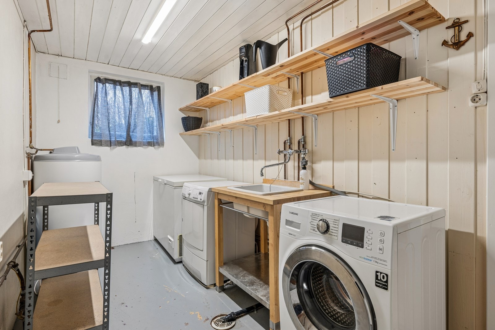 Praktisk vaskerom i underetasjen med benk, vask og opplegg for vaskemaskin. Galleribilde