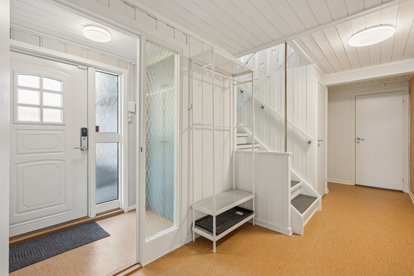 Lys entré i første etasje med trapp ned til underetasjen. Trappen er fra byggeåret. Galleribilde