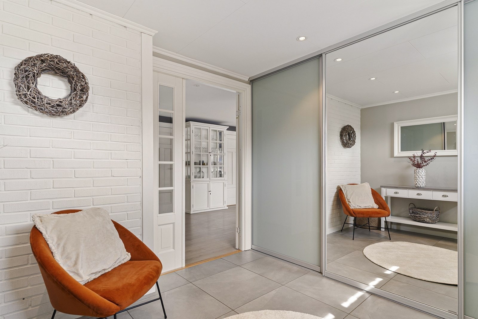 Når du kommer inn i boligen møter du en romslig entré som har skyvedørsgarderobe som går fra gulv til tak. Speilfront på en av tre dører. Galleribilde