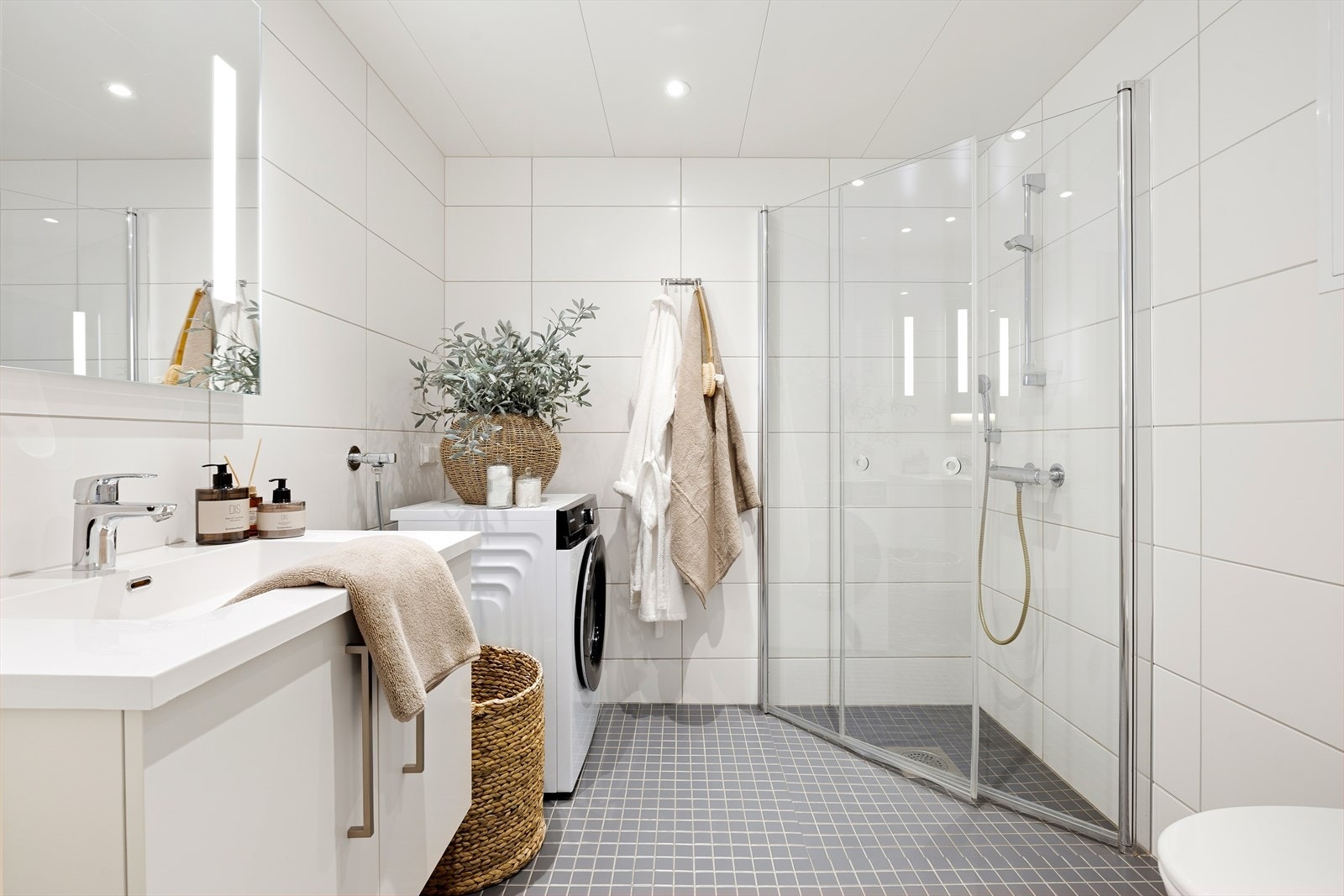 Det 4,5 m² delikate badet fremstår som innbydende med helflisede overflater, behagelig gulvvarme og downlights i tak. Galleribilde