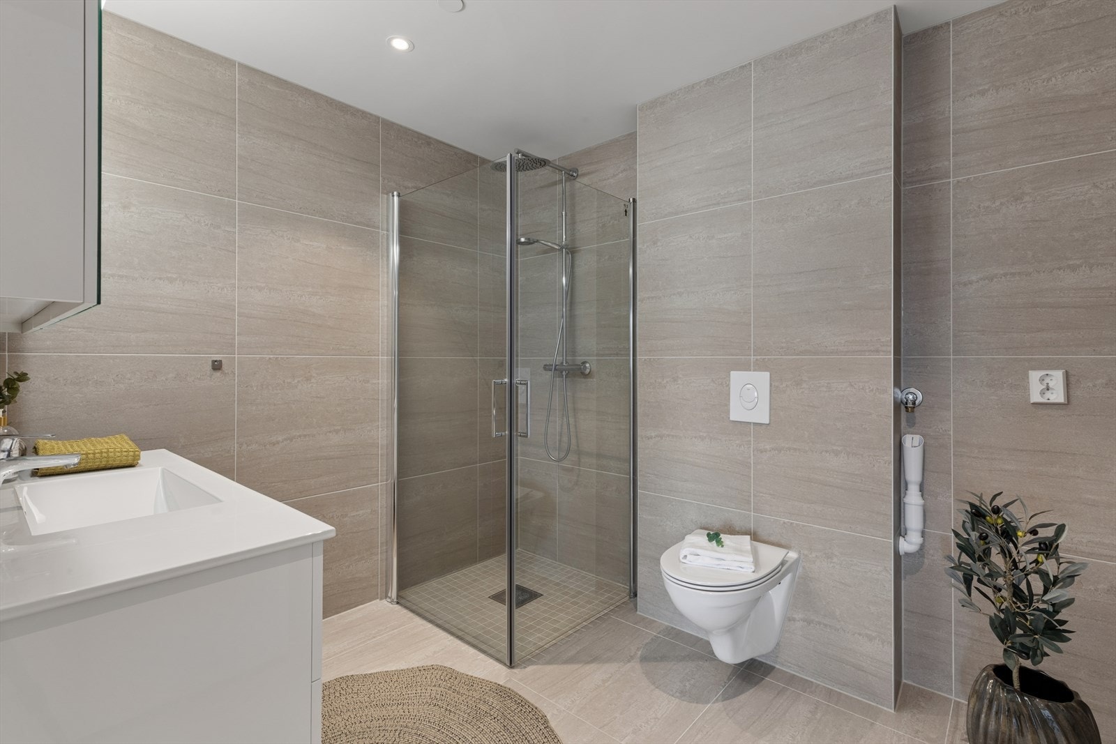 Badet har dusjhjørne med innfellbare vegger, vegghengt toalett og opplegg for vaskemaskin. Galleribilde