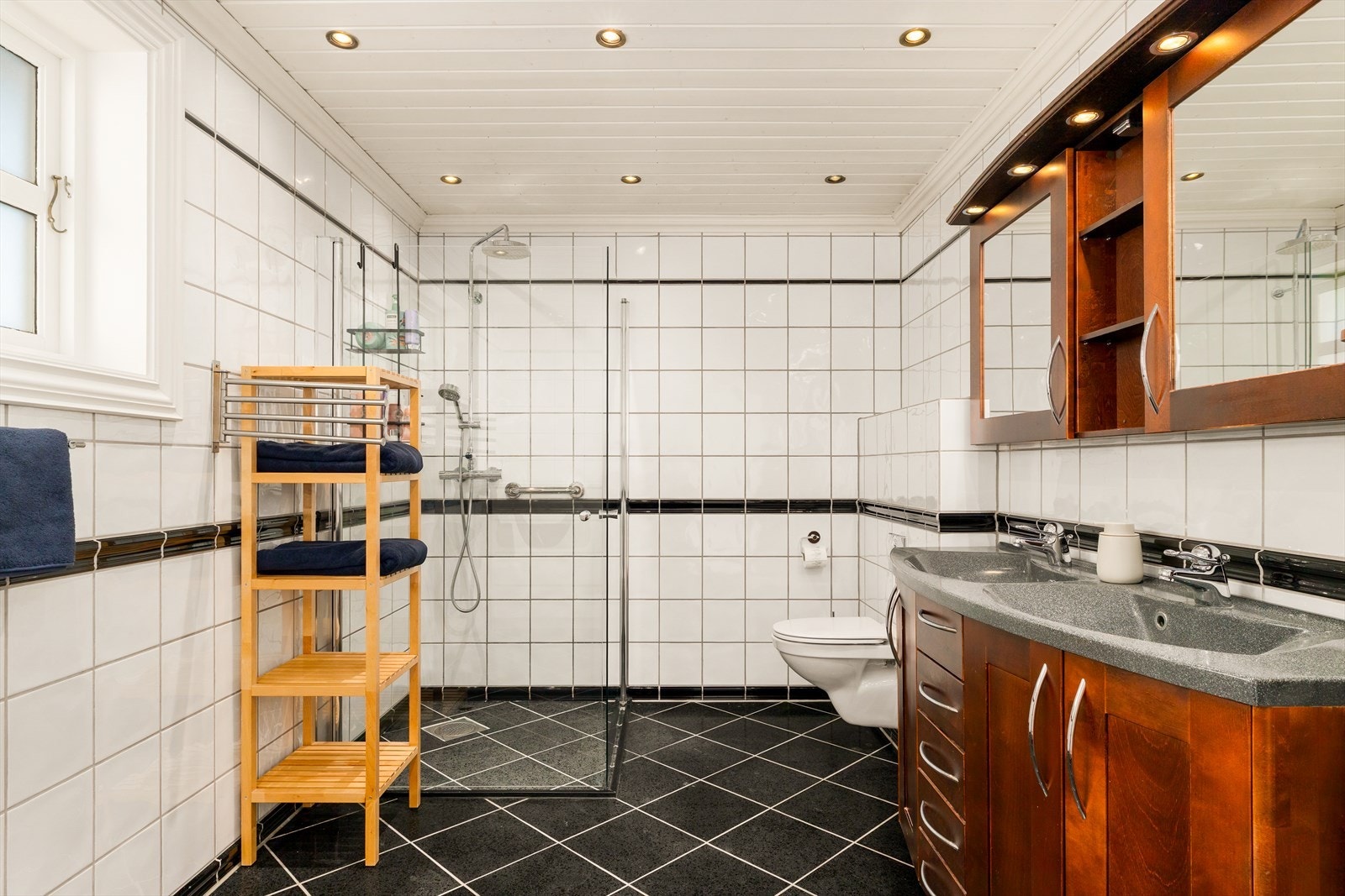 Badet i 1.etasje er innredet med baderomsinnredning med nedfelt servant, gulvstående toalett og dusjløsning med dusjvegger i glass. Galleribilde