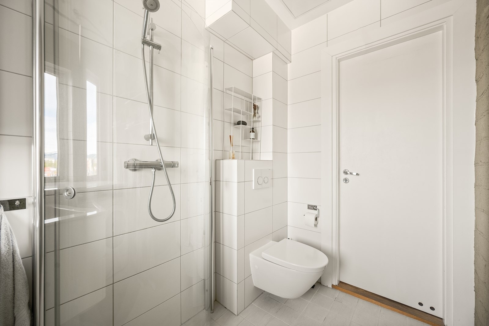 Badet er innredet med vegghengt toalett, servant med innredning, dusjhjørne og opplegg for vaskemaskin. Galleribilde