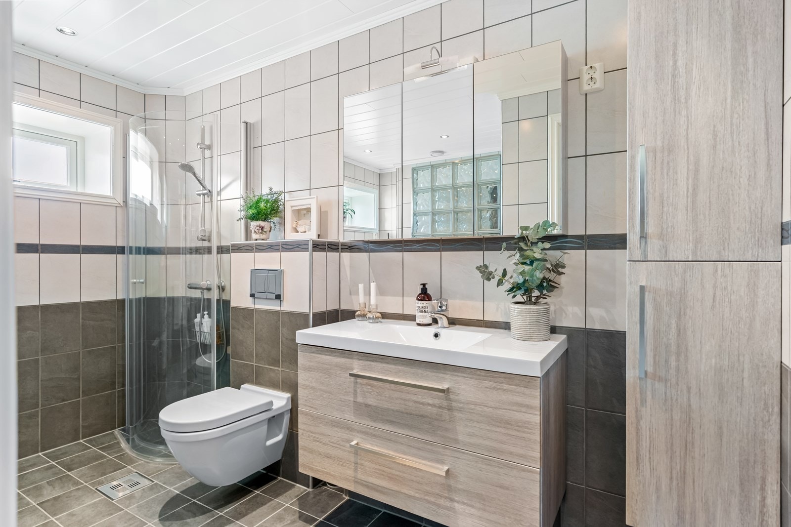 Badet ble pusset opp i 2017, og er smakfullt innredet med vegg- og gulvfliser i ulike grånyanser. Galleribilde