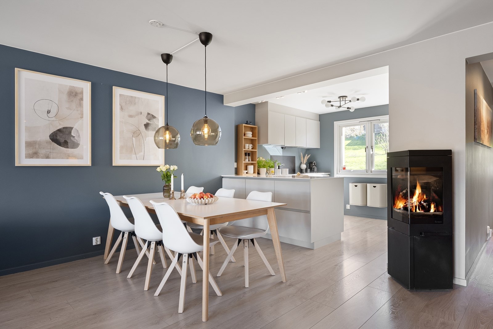 Spisestuen er et naturlig samlingspunkt mellom kjøkkenet og stuen, med en peisovn som gir ekstra varme og hygge. Galleribilde