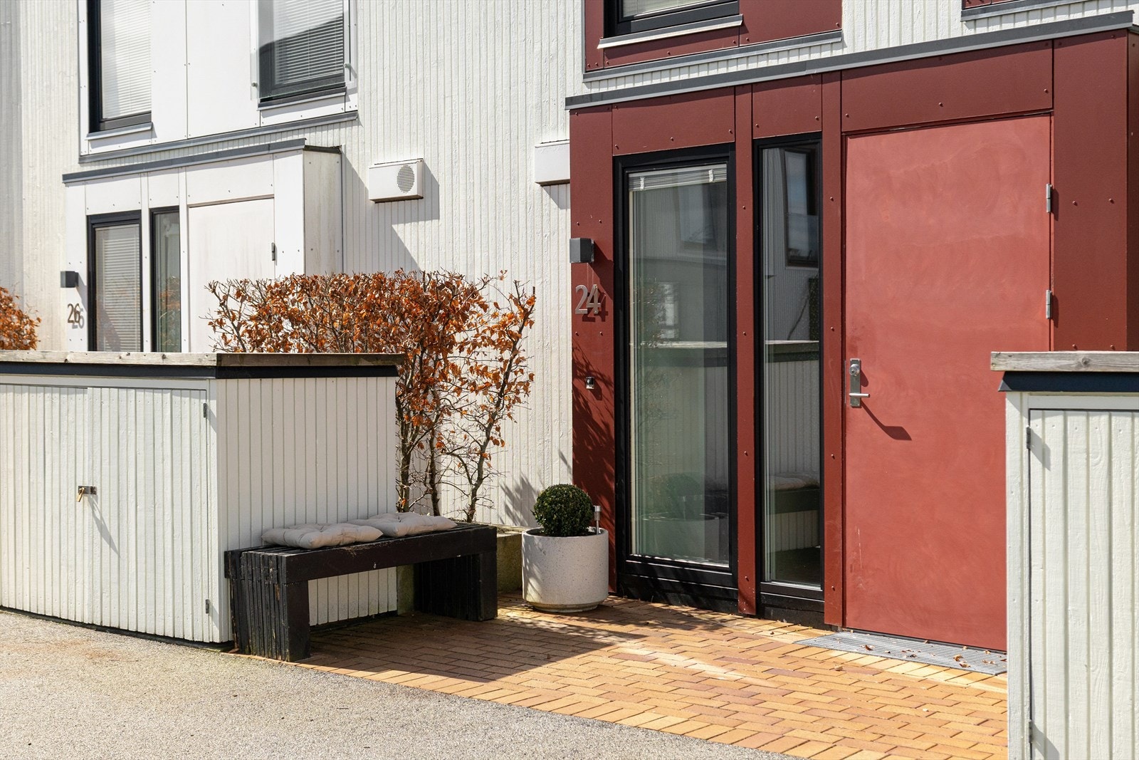 Pent steinbelagt inngangsparti med sittegruppe og beplantning. Galleribilde