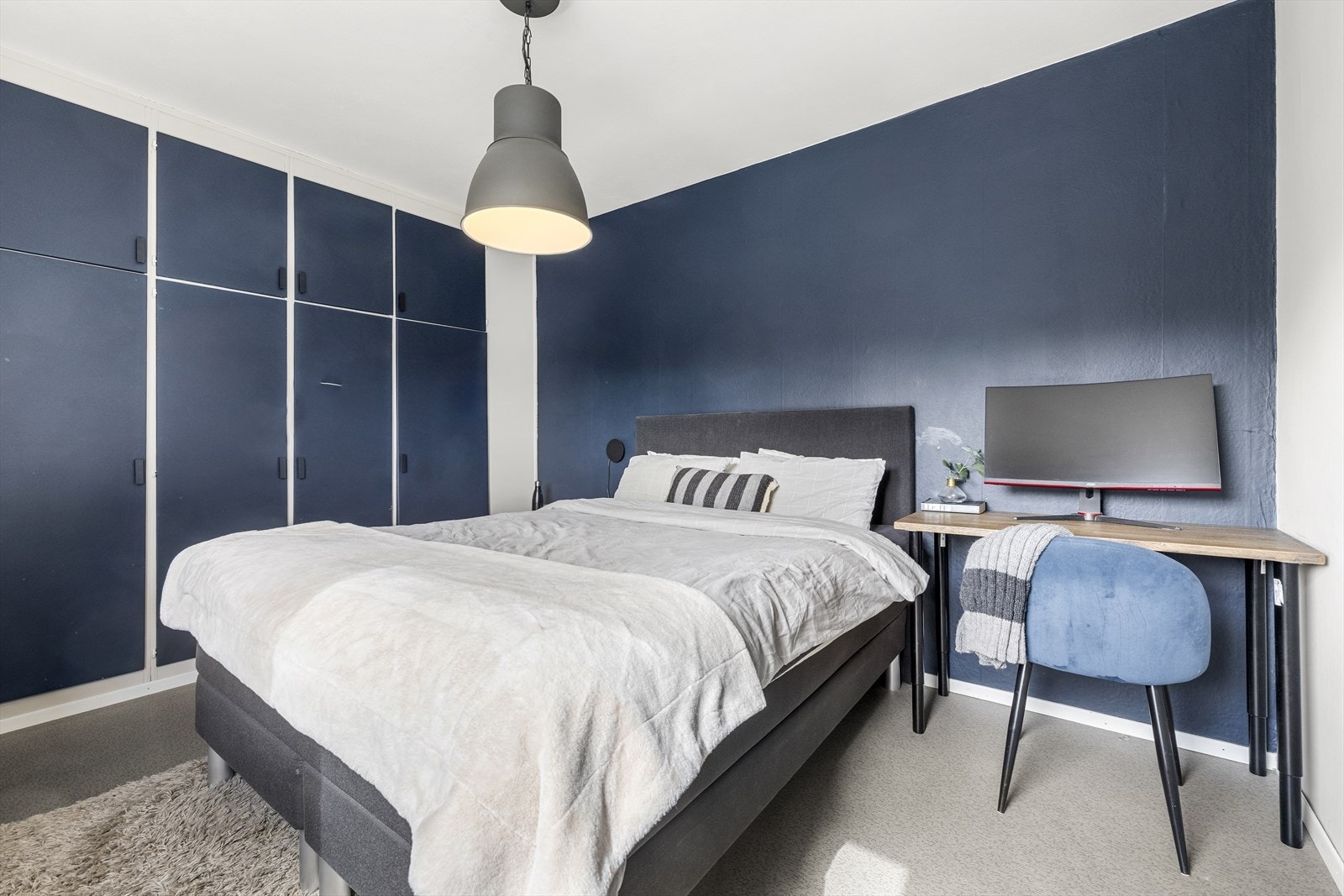 Leiligheten har et romslig og innbydende soverom malt i blått og beige. Galleribilde