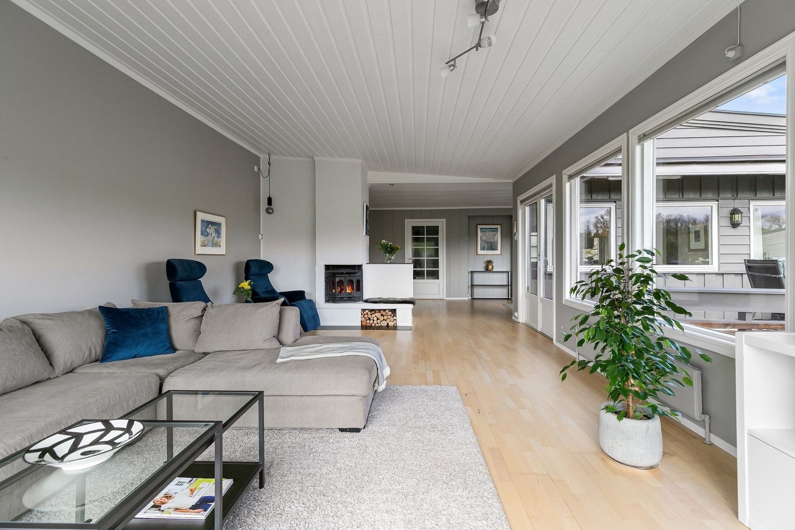 Stor og lys stue med flere soner, peis i hjertet av rommet og utgang til terrasse Galleribilde