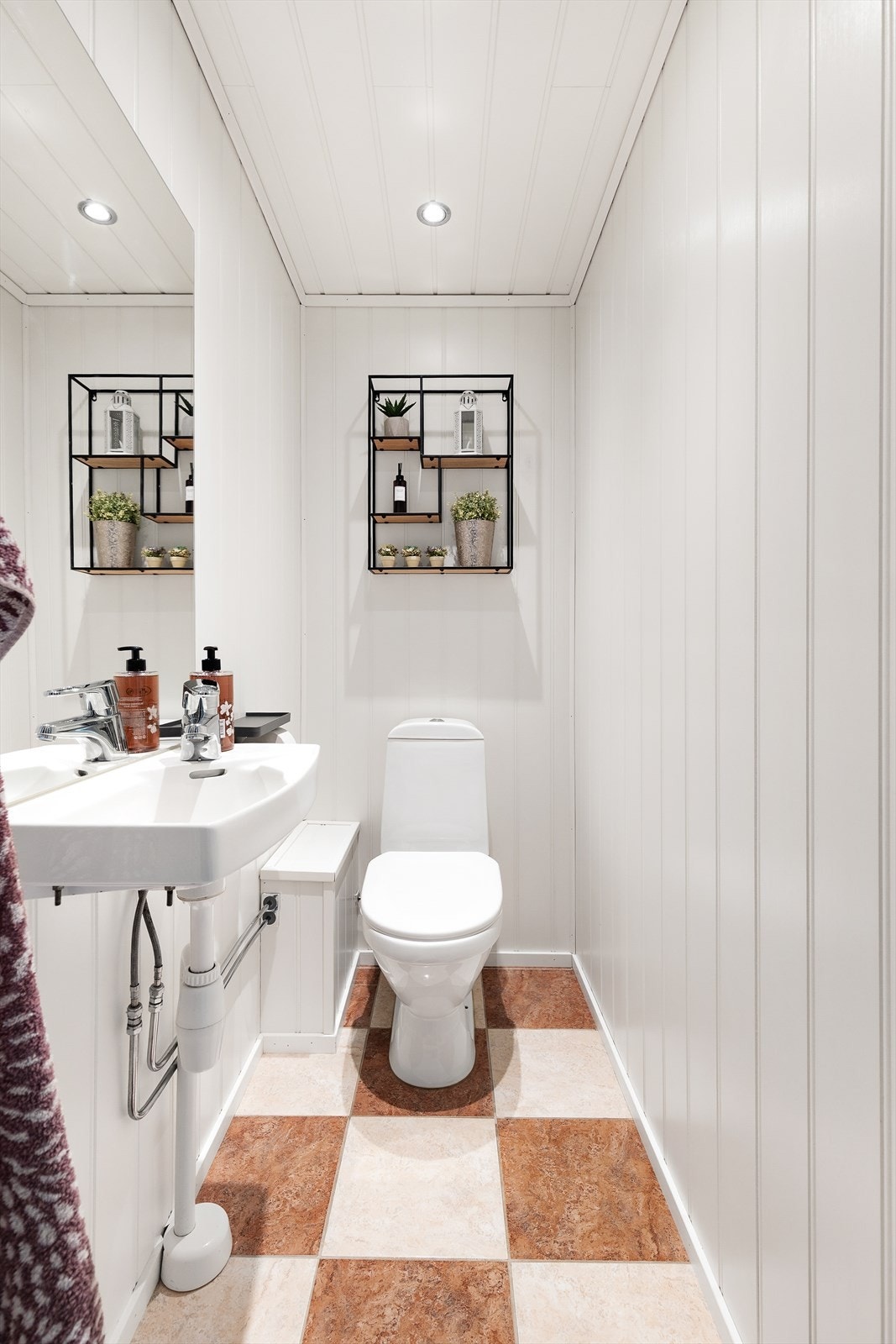 Separat toalettrom med klosett, servant og panel på veggene. Himlingen har innfelte downlights. Galleribilde