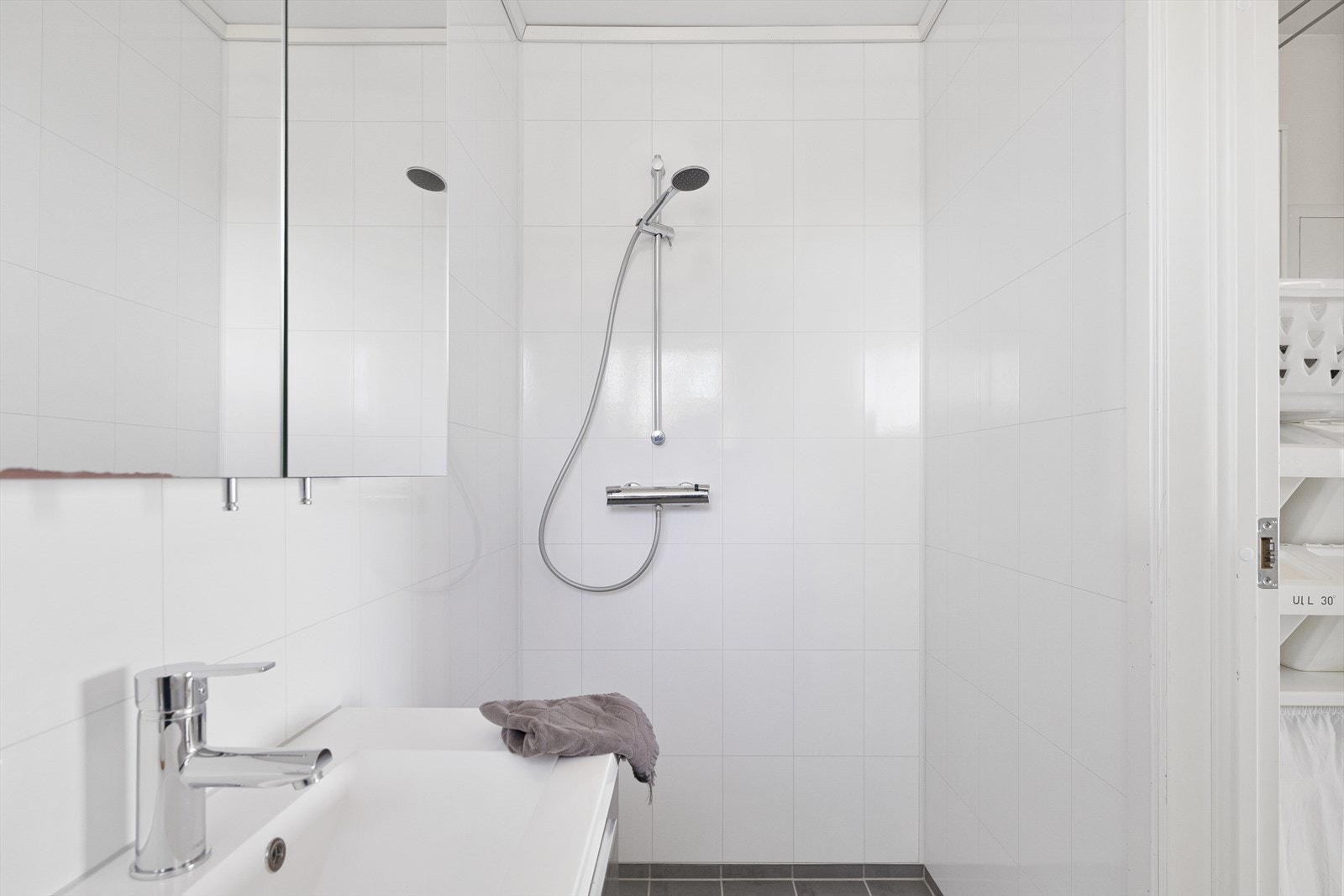 Badet er innredet med vegghengt toalett, servant med underskuffer, speilskap samt dusjhjørne. Galleribilde