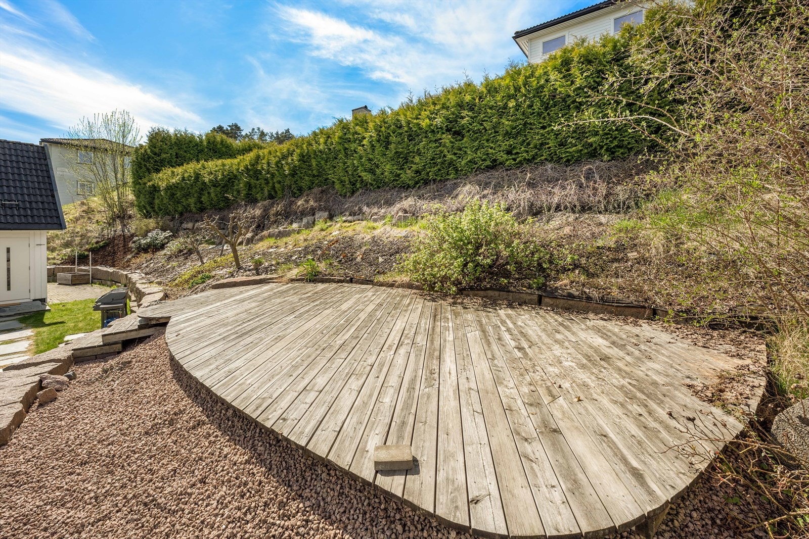 Tomten er opparbeidet med gressplen, beplantning og flere plattinger. Galleribilde