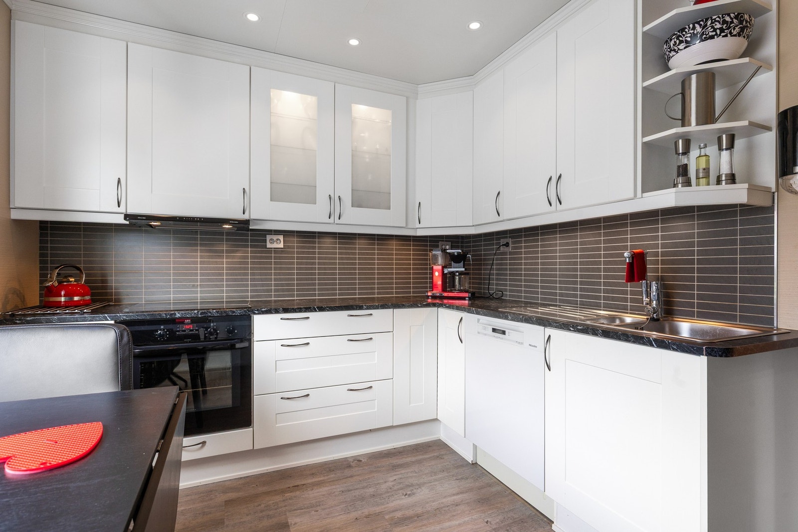 Tidløst kjøkken med takhøye overskap og downlights i taket. En smakfull backsplash bryter fint med de nøytrale kjøkkenfrontene. Galleribilde