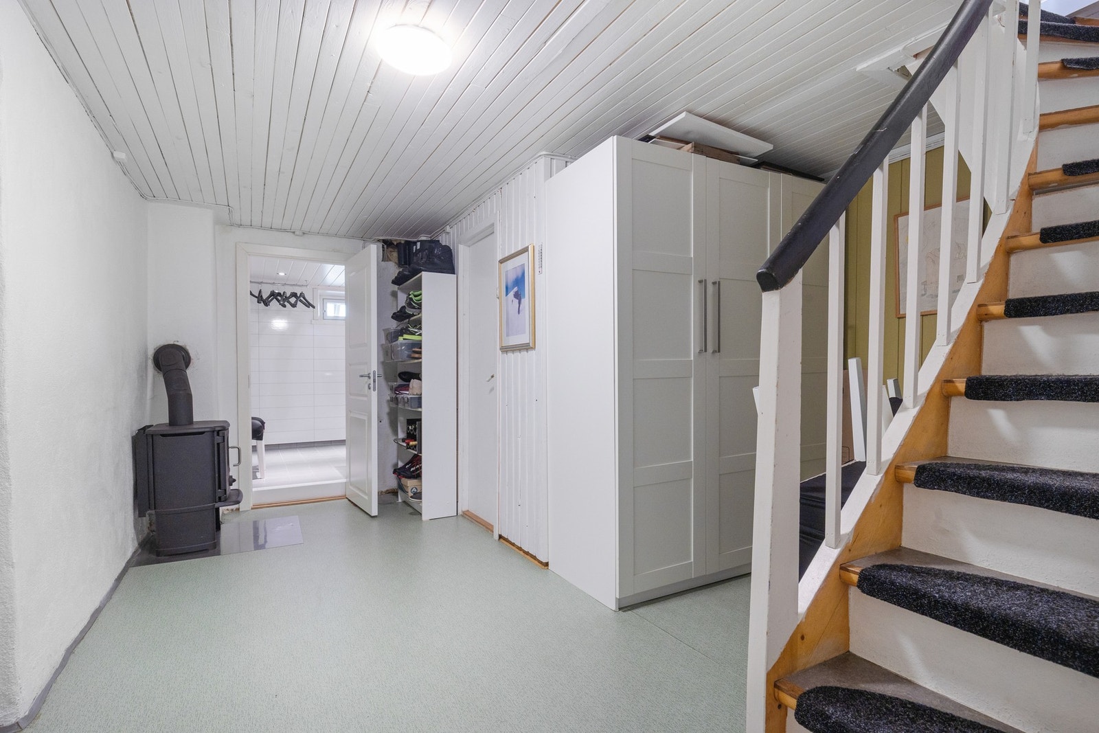 Vi har beveget oss ned kjellertrappa og skal nå vise deg kjelleren. Her i gangen ser du at det finnes en vedovn. Galleribilde