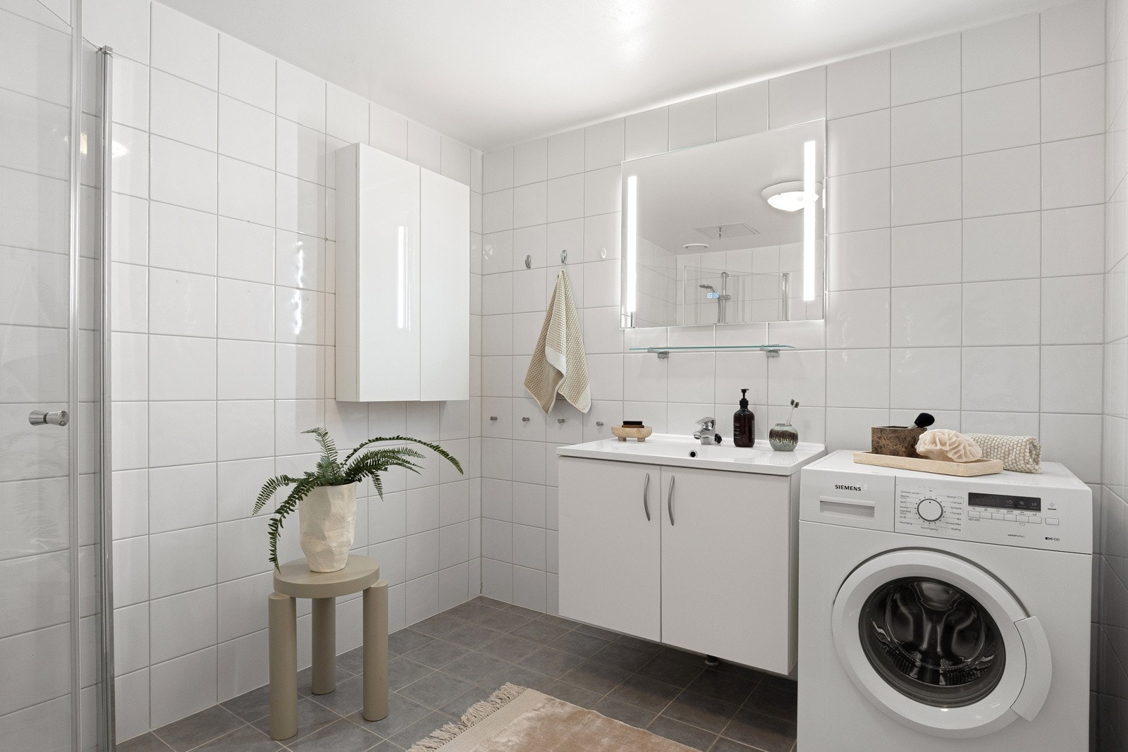 Stort, lyst og innbydende flislagt bad med varmekabler i gulv. Speil med lysarmatur over servant, gode lagringsmuligheter, samt opplegg for vaskemaskin. Mekanisk avtrekk. Galleribilde