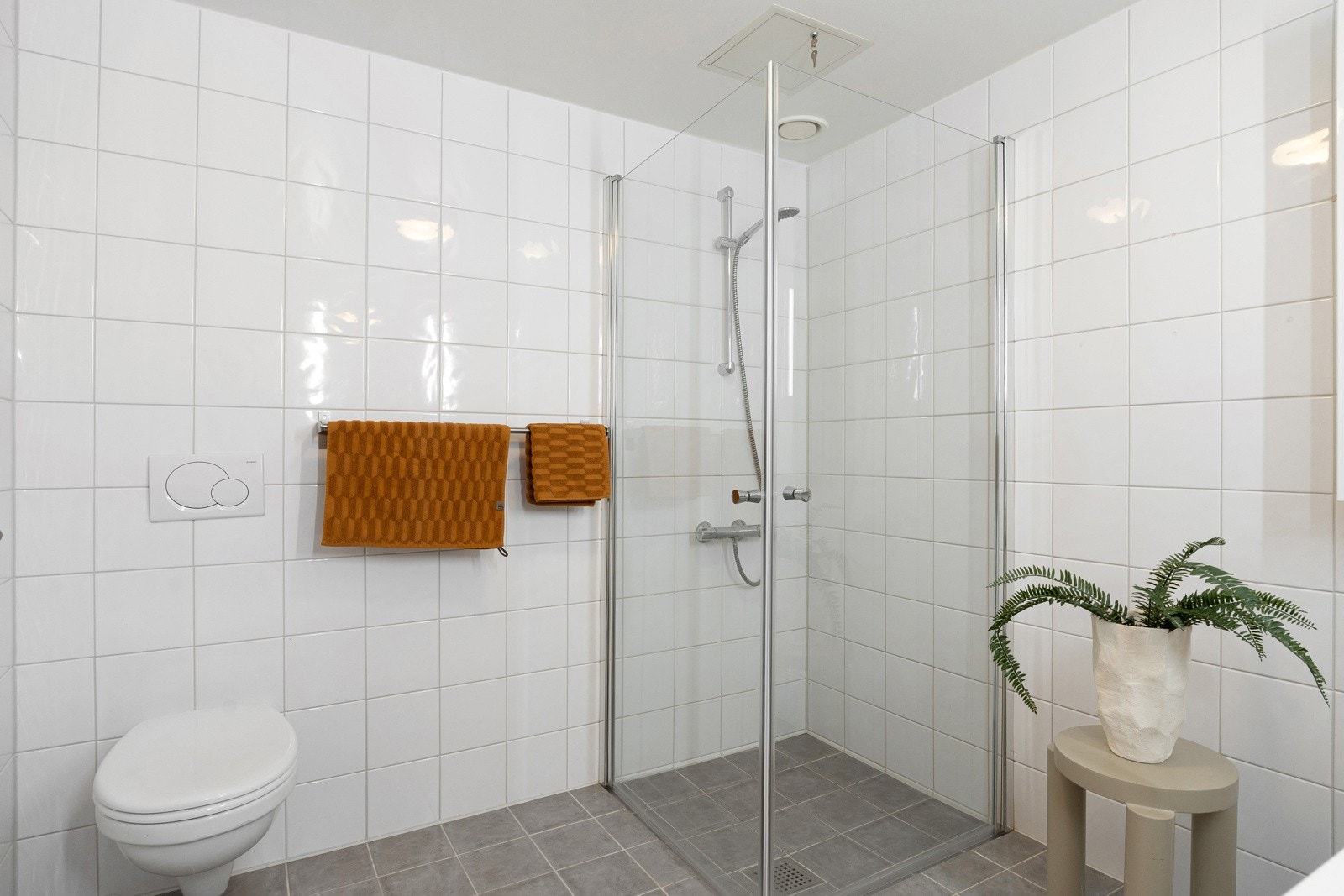Badet er utstyrt med dusjhjørne, vegghengt toalett og servantskap med glatte fronter og heldekkende servant. Galleribilde
