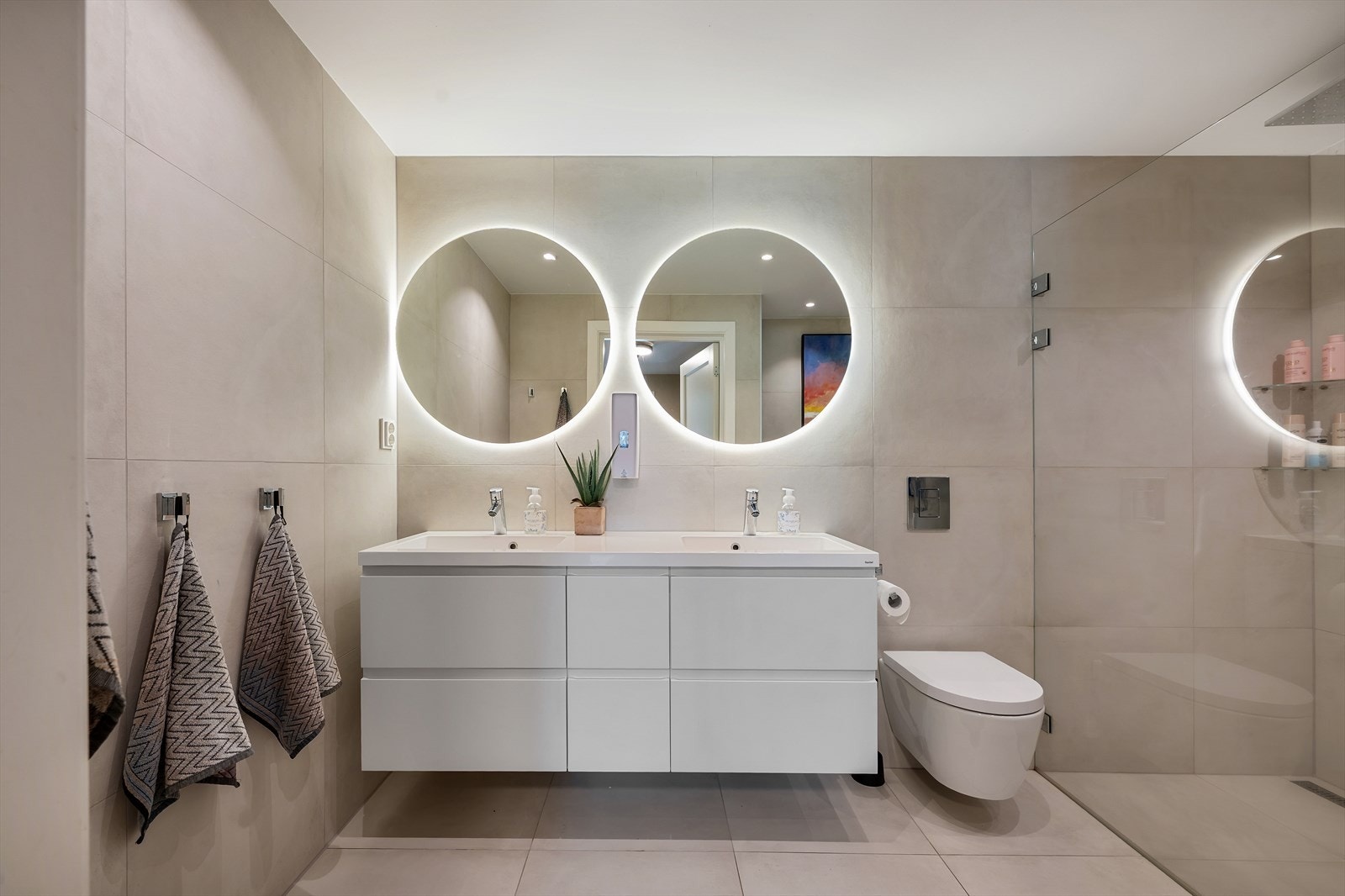 Videre har badet regnfallsdusj med glassdører og badekar - perfekt for både store og små Galleribilde