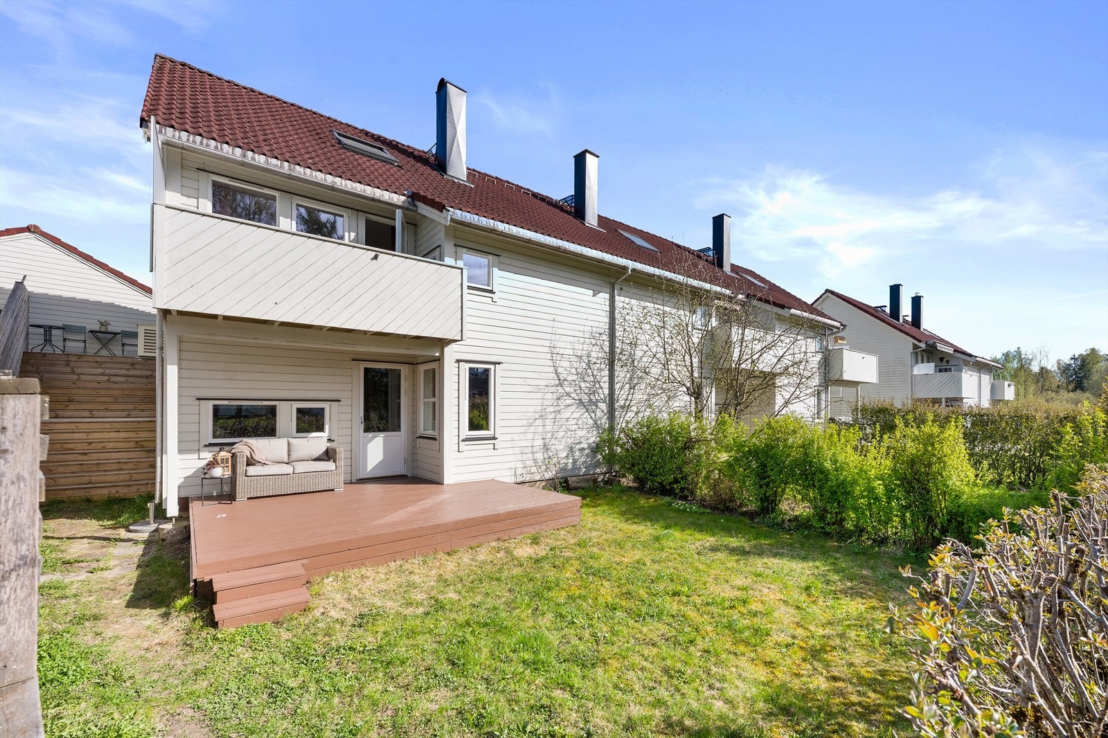 På bakkeplan er det terrasse med utgang direkte fra underetasjen, videre ut til tilhørende hage med gressplen og beplantning - et ideelt leke- og oppholdsareal for både barn og voksne Galleribilde