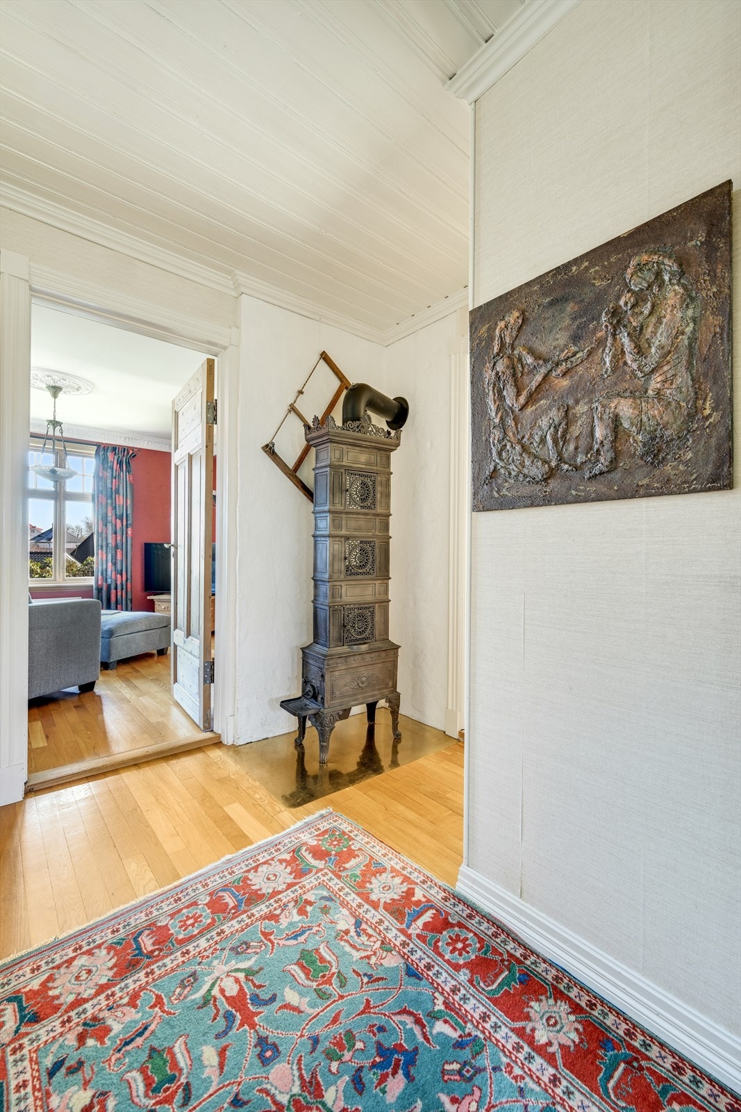 Gangen i første etasje har parkett på gulvet og en klassisk etasjeovn. Galleribilde