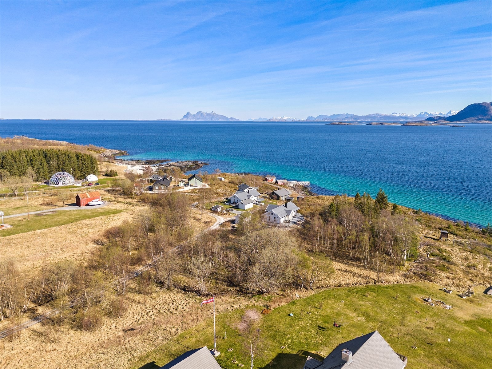 Området ser vidt utover havet, med den karakteristiske profilen av øyer og fjell i horisonten. Galleribilde