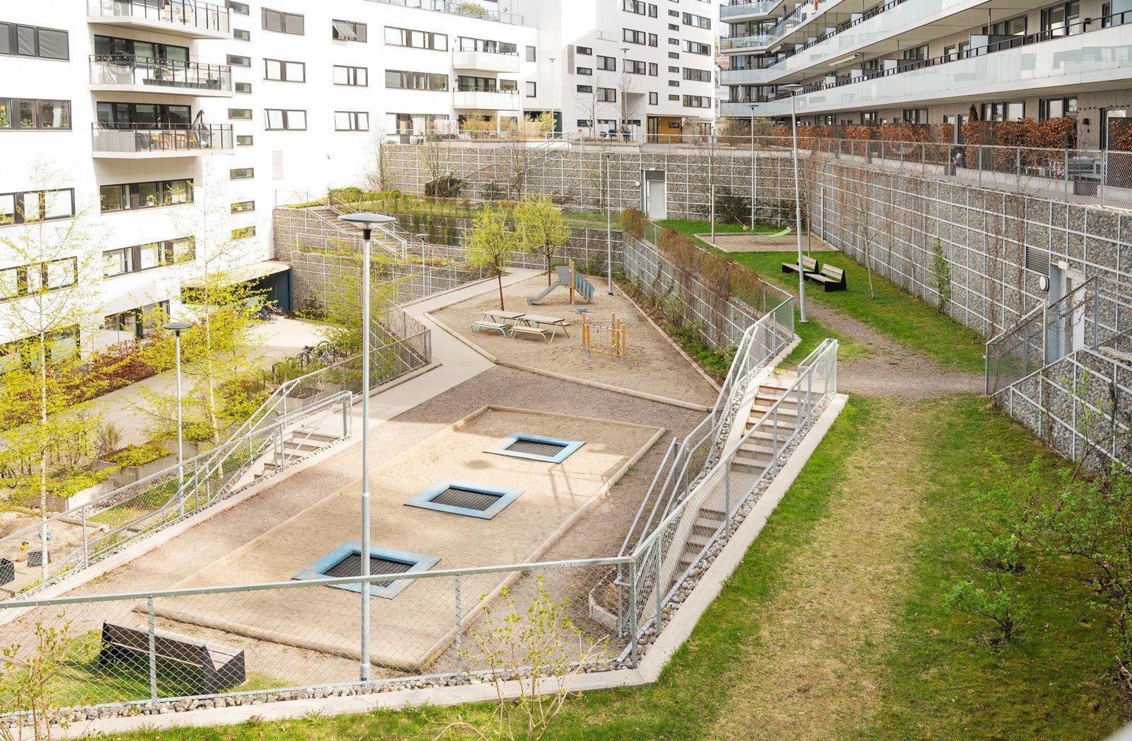 Bakgården er pent opparbeidet med plen, lekeapperater, benker og beplantning Galleribilde