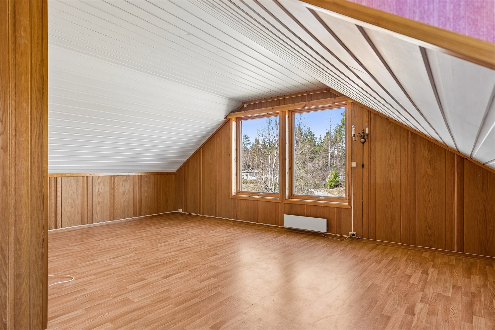 Loftstuen har trepanel på deler av veggene og laminat på gulvet. Galleribilde