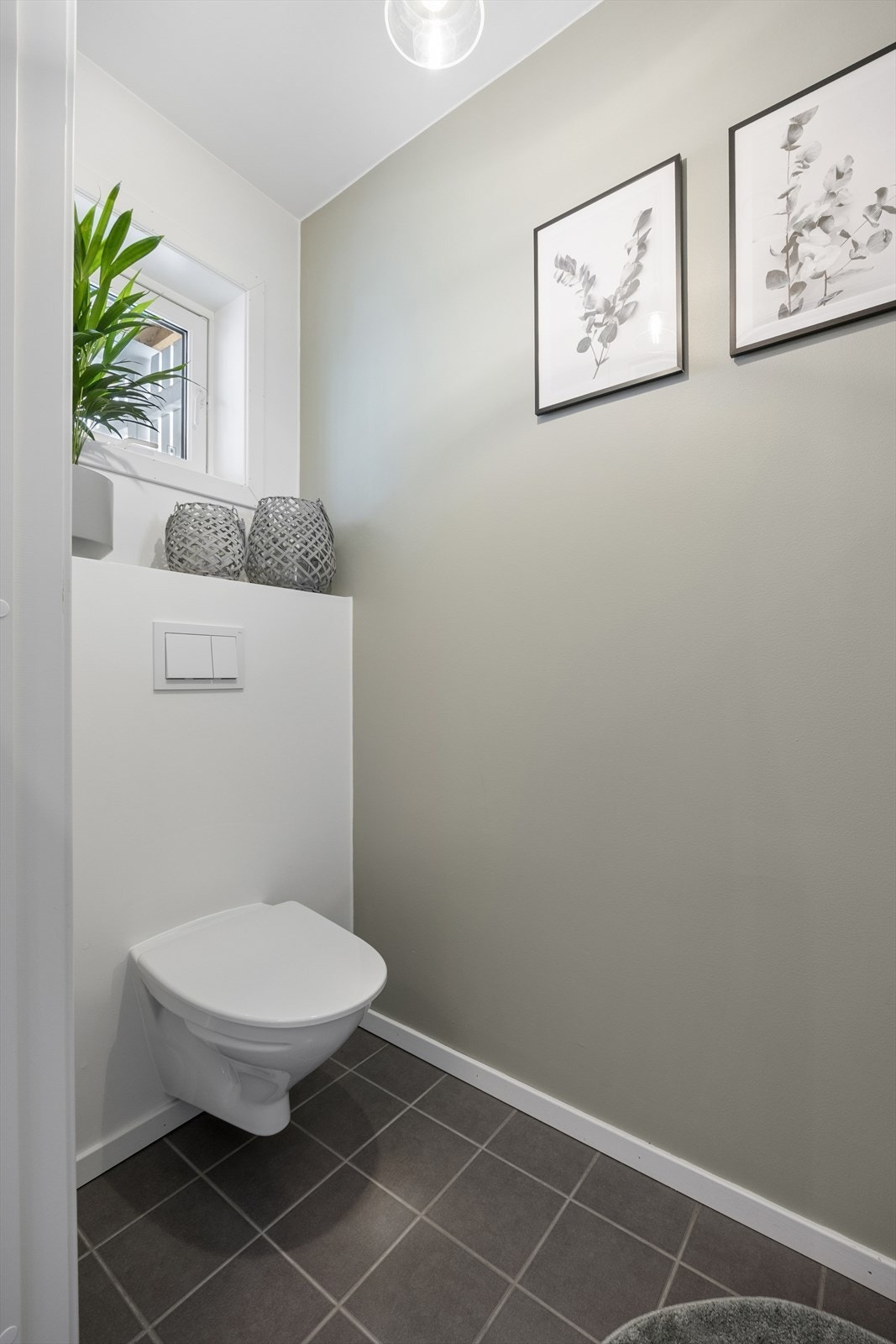 Her finner du gjeste-WC med flislagt gulv og lyse overflater. Galleribilde