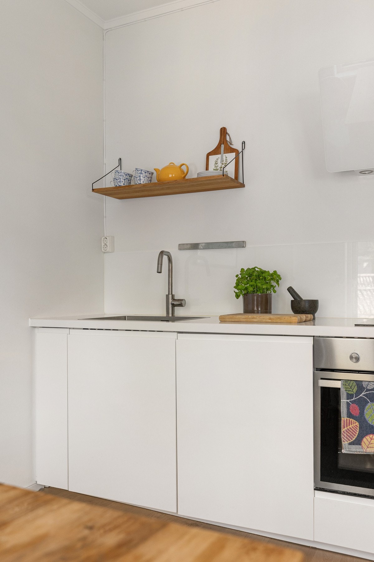 Stilren kjøkkeninnredning med laminerte skrog og slette fronter. Kjøkkenet har laminat benkeplate med nedfelt oppvaskkum, samt glassplate på vegg over benkeplate. Galleribilde