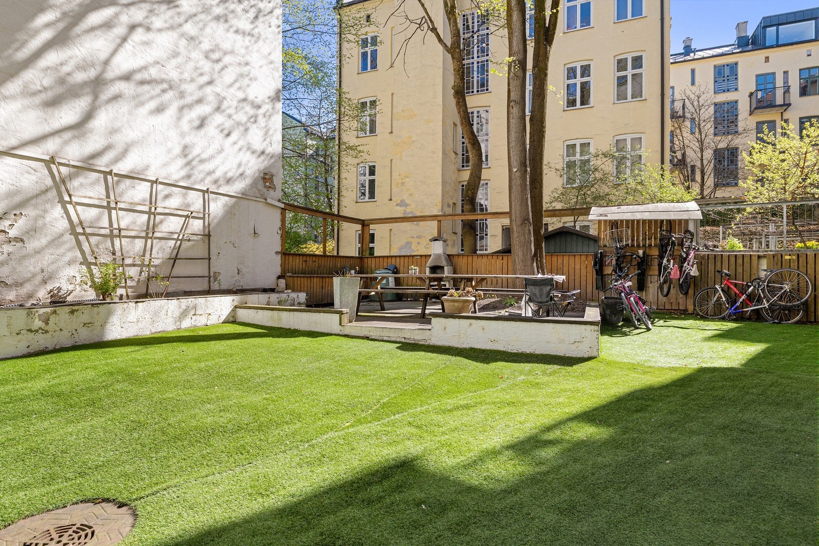 Hyggelig felles bakgård med sittebenker, grillplass og beplantning Galleribilde
