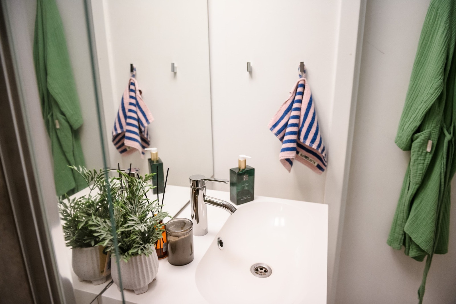 Badet har servant på hvit skuffeseksjon, speil med overlys, et dusjhjørne, toalett og opplegg for vaskesøyle. Galleribilde