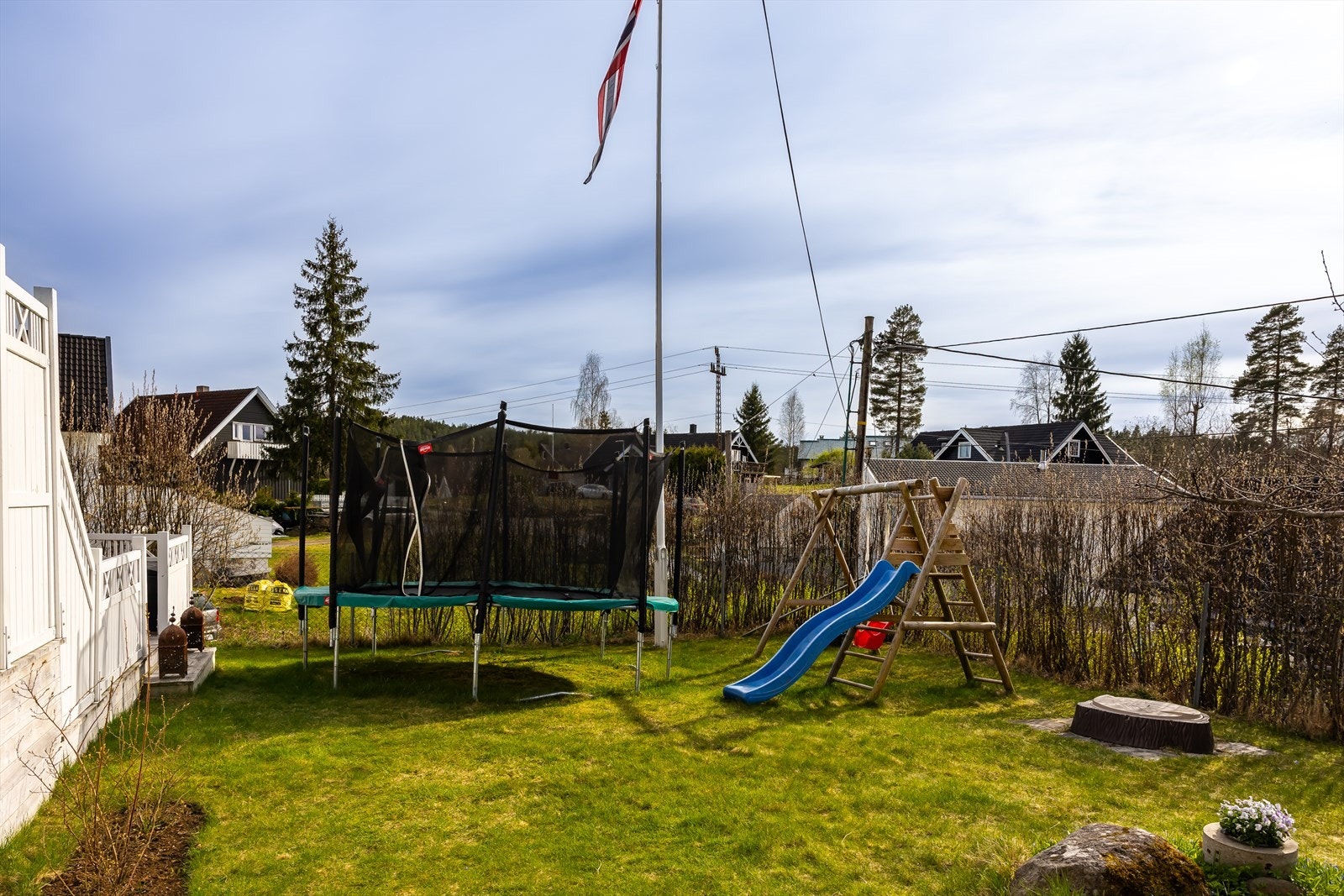 Barnevennlig hage med trampoline, lekestativ med husker og sklie, samt sandkasse og gode lekeområder. Galleribilde