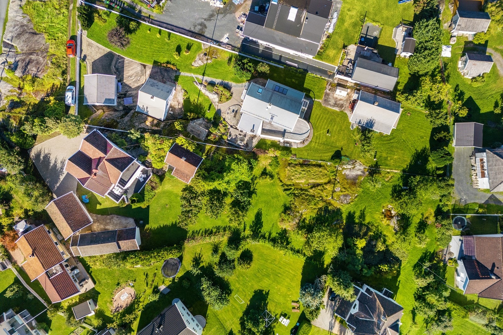 Tomten er opparbeidet med belegningsstein på gårdsplass, gressplen og variert beplantning på store deler av eiendommen. Galleribilde