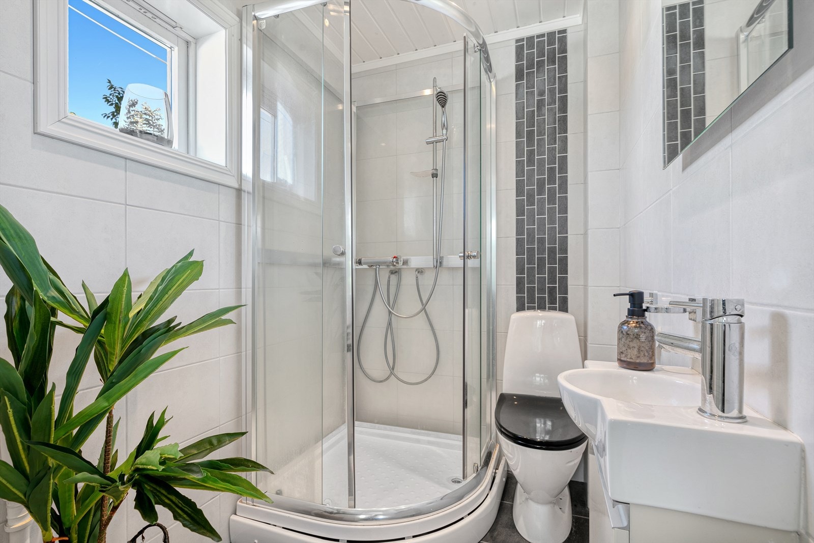 Badet i 1. etasje er innredet med en baderomsinnredning med servant, speil, toalett og dusjkabinett. Her er det også opplegg for vaskemaskin. Galleribilde