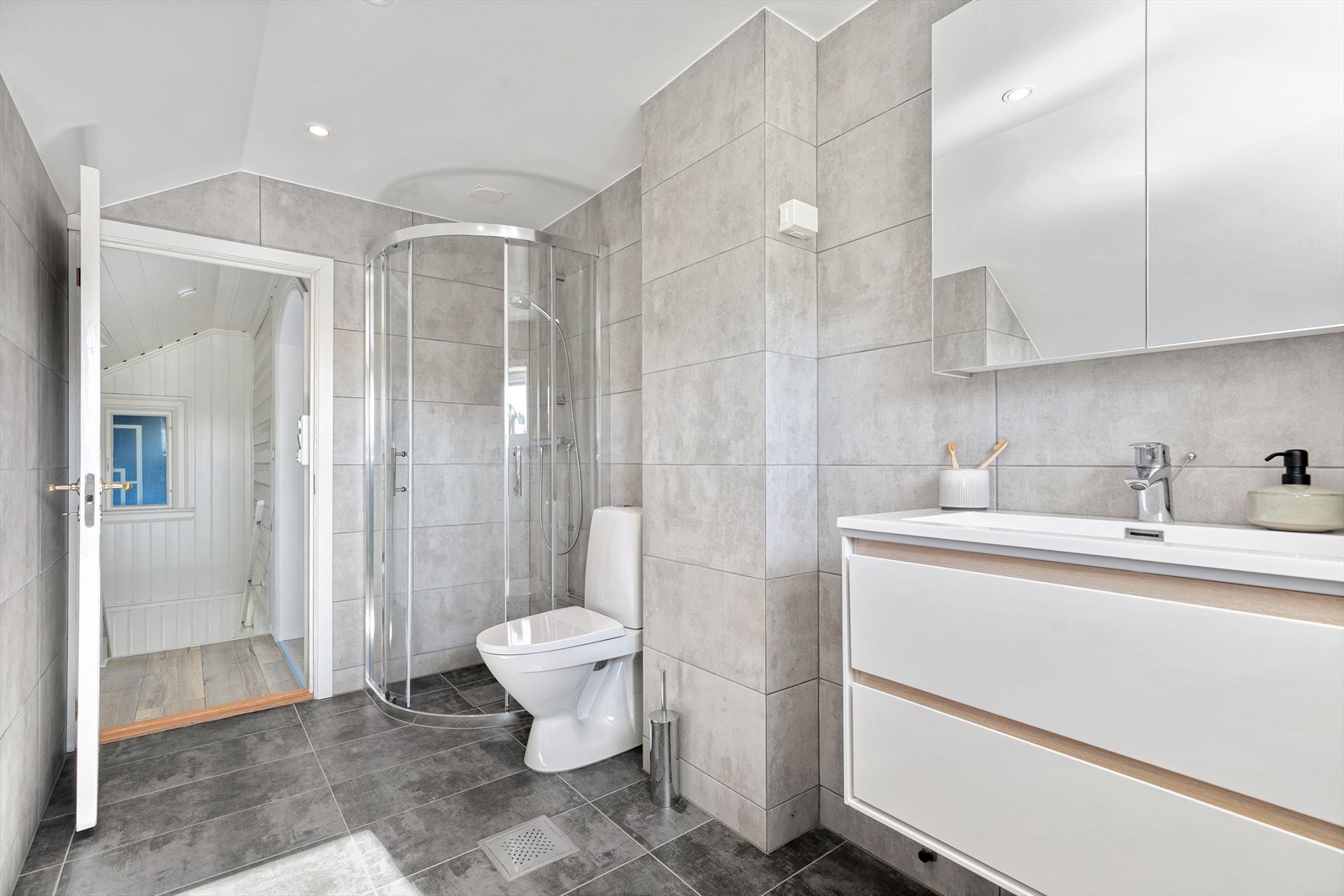 Badet er ellers innredet med en stilren baderomsinnredning med heldekkende servant, speilskap med belysning og toalett. Galleribilde