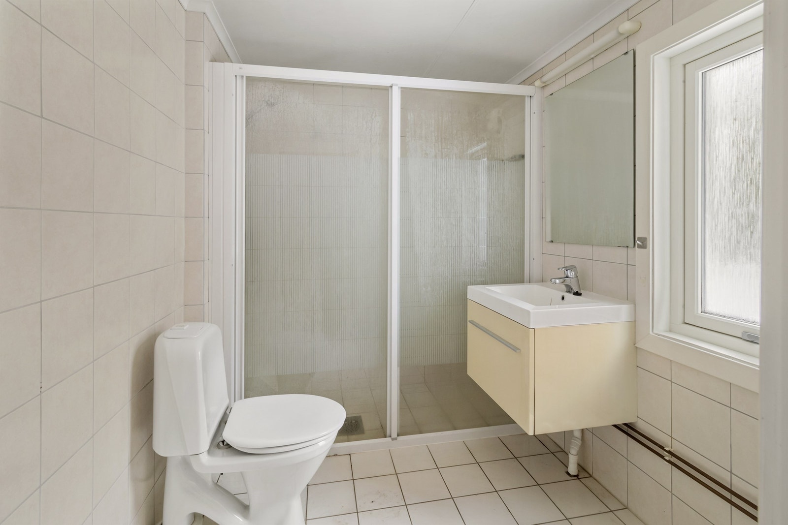Badet i første etasje har flislagte overflater, dusjløsning og opplegg for vaskemaskin. Galleribilde