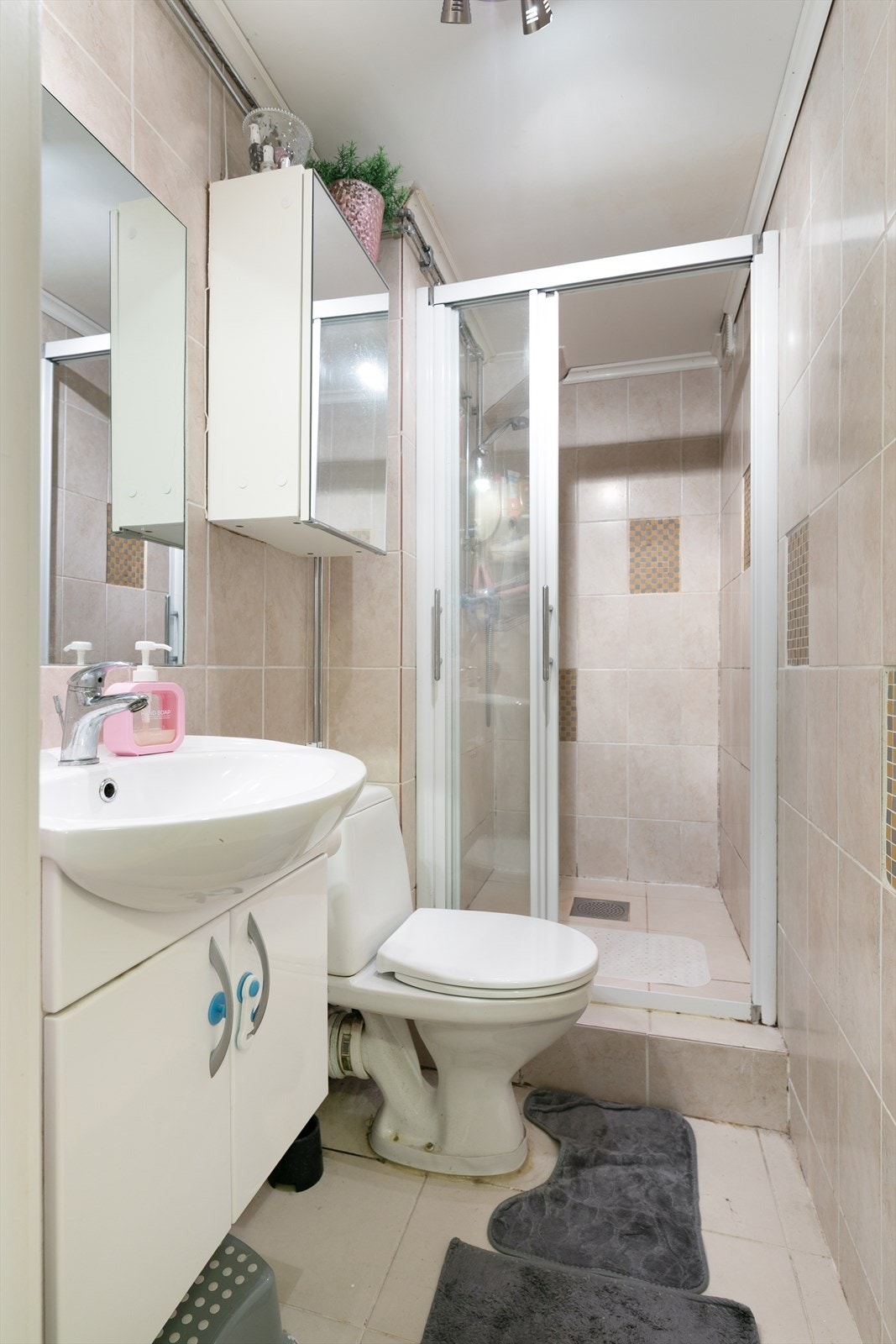 Badet i underetasjen er flislagt og utstyrt med dusjkabinett, servant og toalett. Galleribilde
