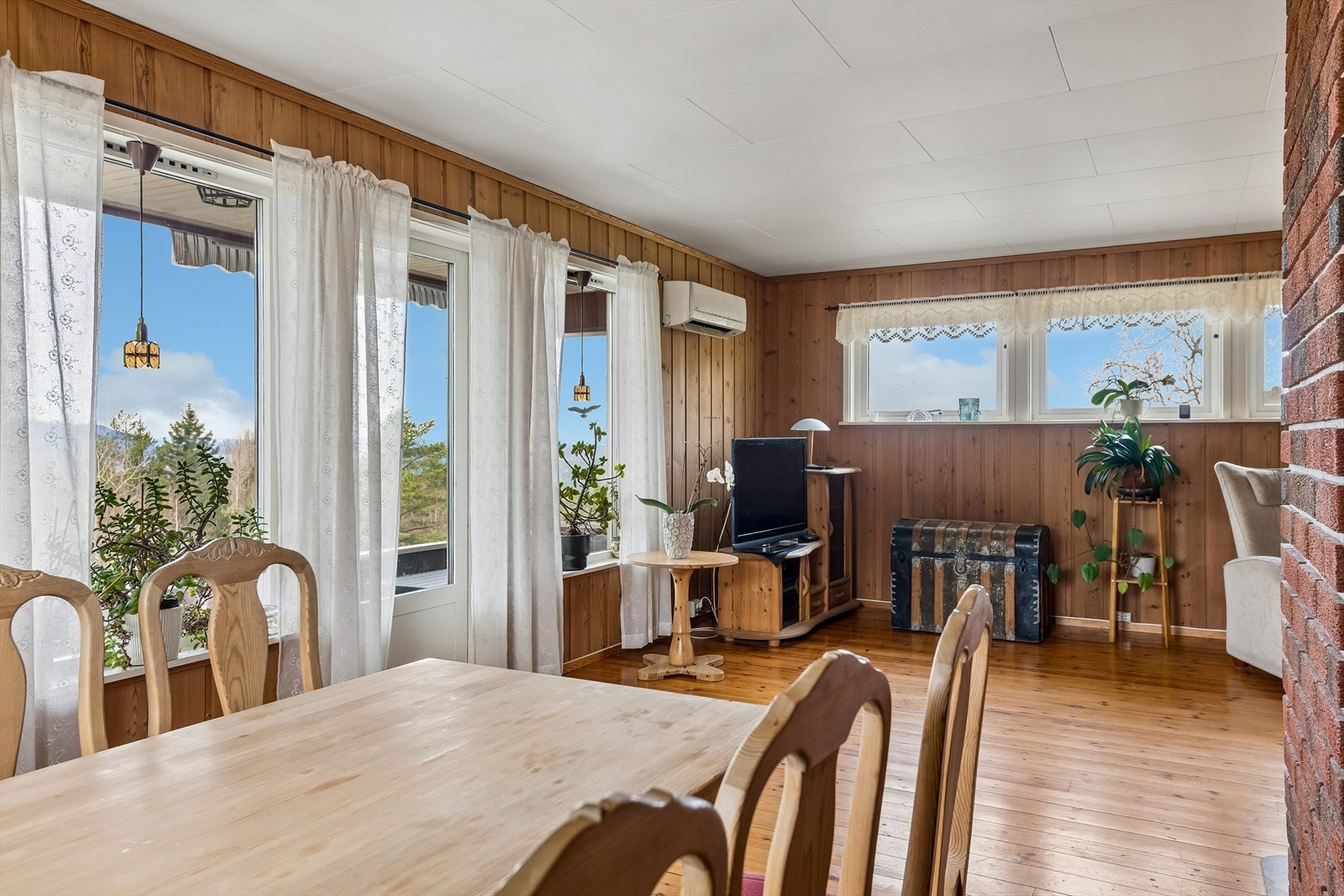 Store vindusflater slipper inn dagslys og rammer inn utsikten mot skog og landskap. Galleribilde
