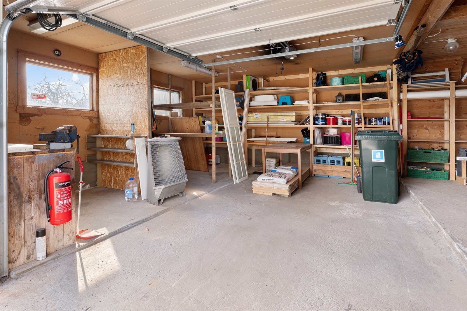 Garasjen er på 42 kvm og er godt tilrettelagt med hyller for lagring og en praktisk arbeidsbenk. Her er det rikelig med plass til oppbevaring, samtidig som det er god plass til parkering av én bil. Galleribilde