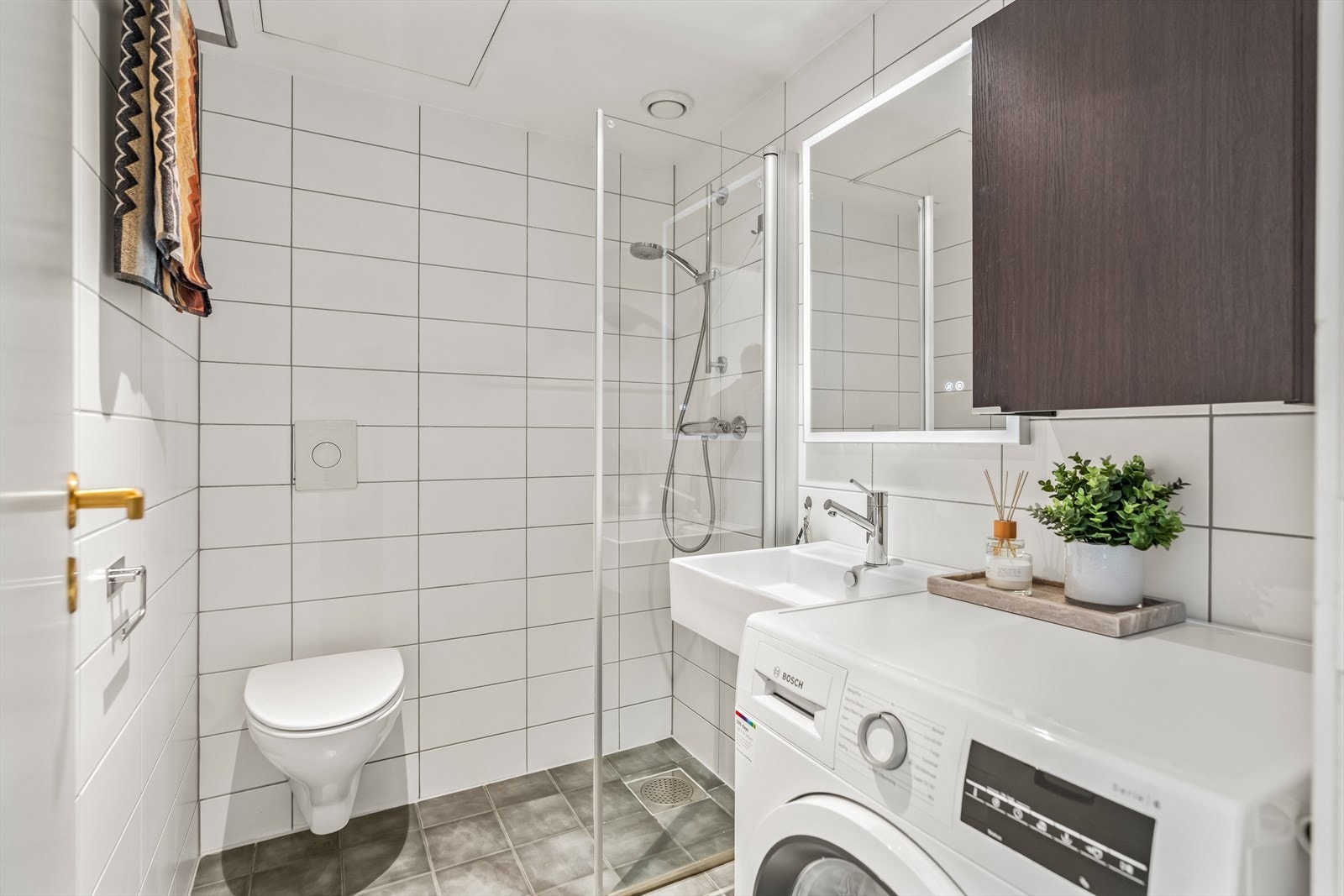 Badet har flislagte overflater. Rommet er utstyrt med servantskap med glatte, folierte fronter og heldekkende servant. Galleribilde