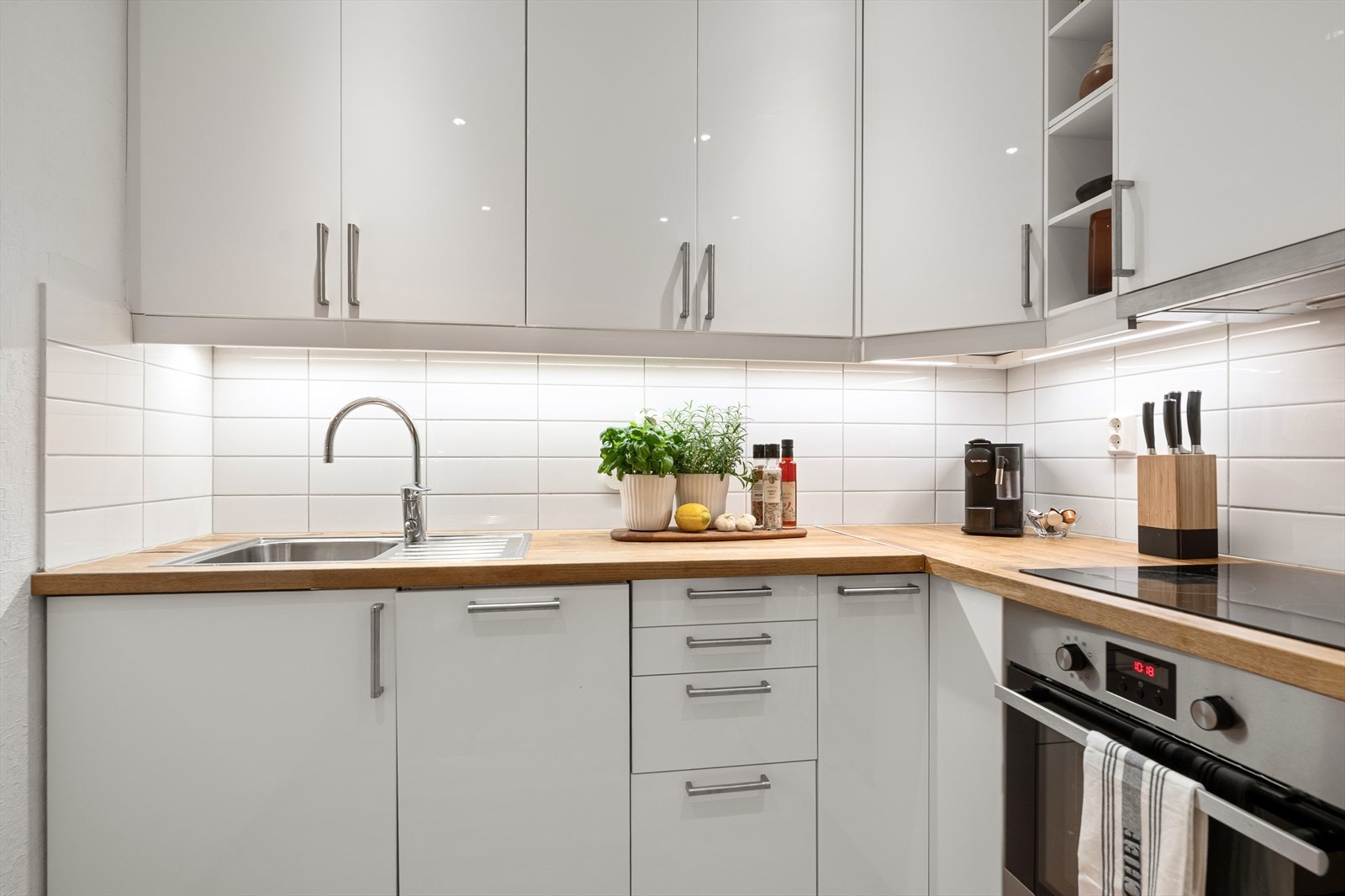 Det er fliser på vegg over benkeskap, benkeplate i laminat med nedfelt kum i rustfritt stål, samt ventilator med avtrekk til ventilasjonskanal Galleribilde